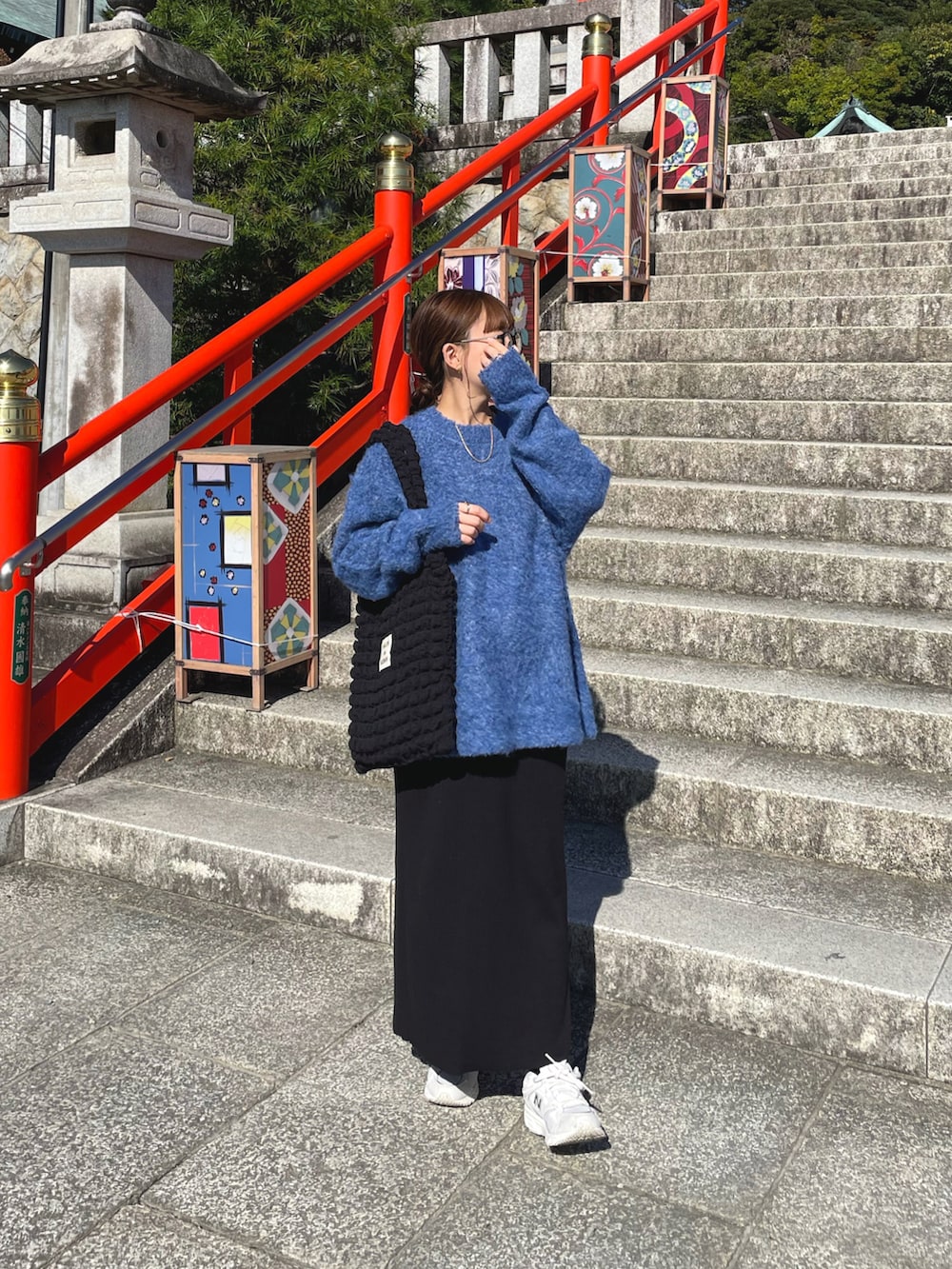 ブルー系のニット/セーター、ブラック系のトートバッグ、ホワイト系のスニーカーを着用したレディースの秋コーディネートの3枚目の写真