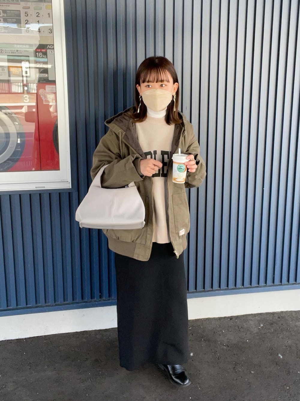 グリーン系のブルゾン、ホワイト系のニット/セーター、ベージュ系のバッグを着用したレディースの秋コーディネートの2枚目の写真