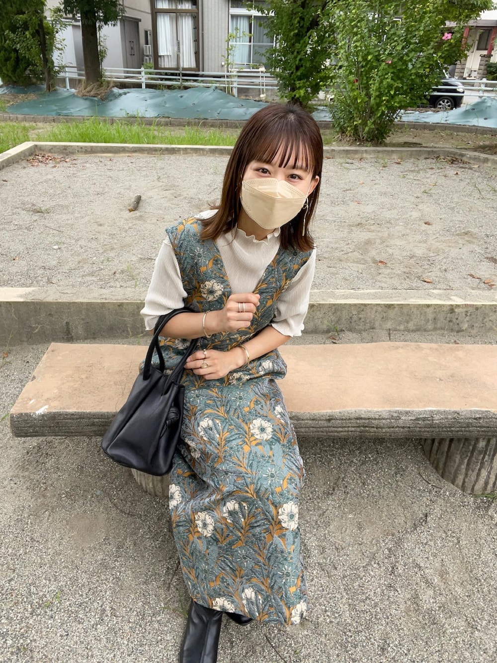 イエロー系のワンピース、ホワイト系のTシャツ/カットソー、ブラック系のハンドバッグを着用したレディースの秋コーディネートの4枚目の写真