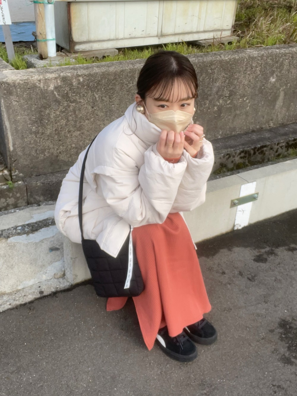 オレンジ系のワンピース、ホワイト系のニット/セーター、ブラック系のショルダーバッグを着用したレディースの冬コーディネートの2枚目の写真