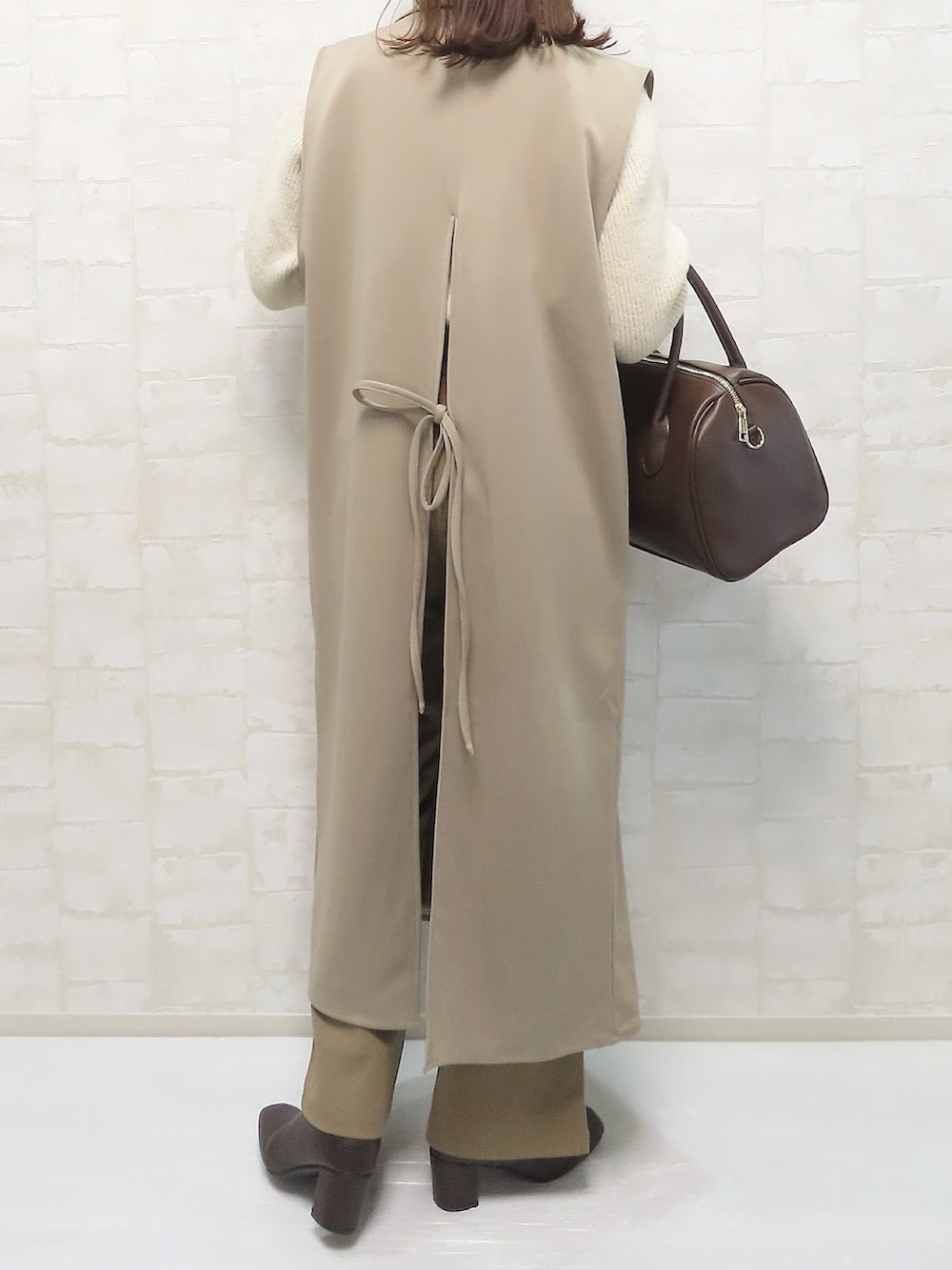 ベージュ系のニット/セーター、ベージュ系のベスト、ブラウン系のパンツを着用したレディースの冬コーディネートの3枚目の写真