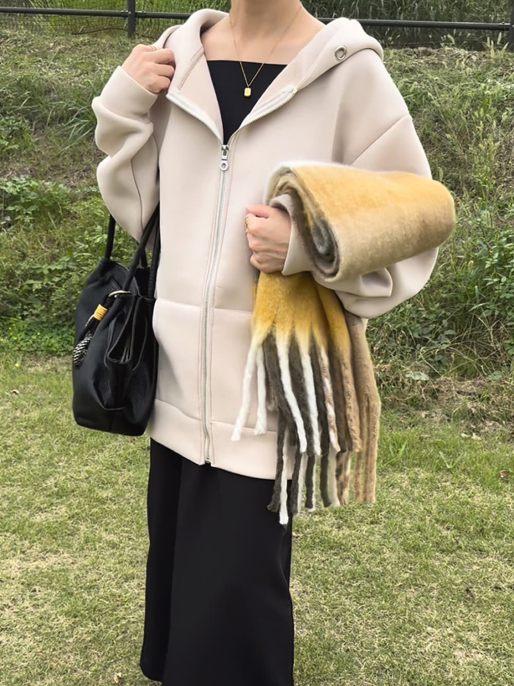 ベージュ系のパーカー、ブラック系のワンピース、ホワイト系のスニーカーを着用したレディースの冬コーディネートの3枚目の写真