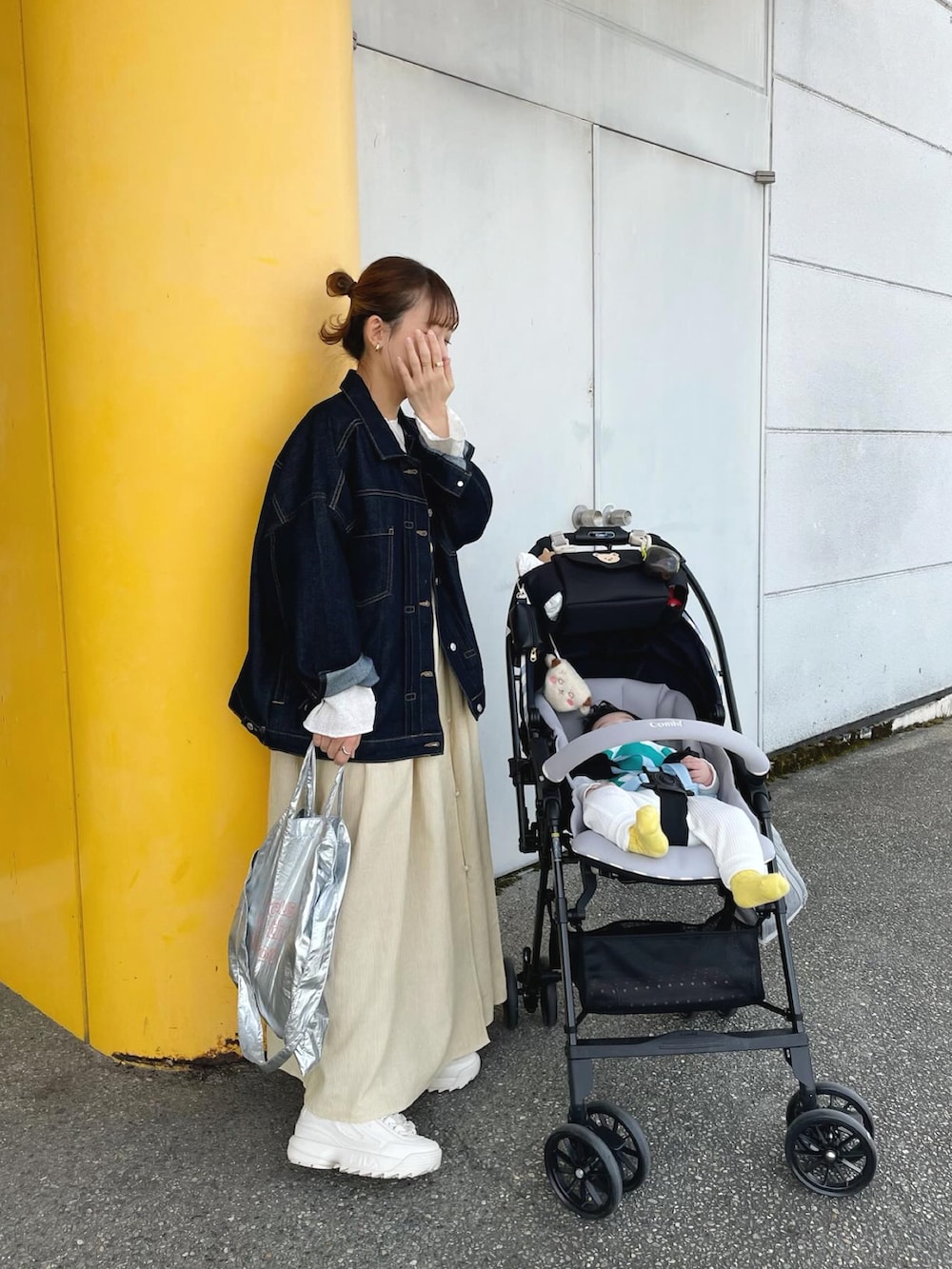 イエロー系のワンピース、ブルー系のデニムジャケット、シルバー系のトートバッグを着用したレディースの春コーディネートの3枚目の写真