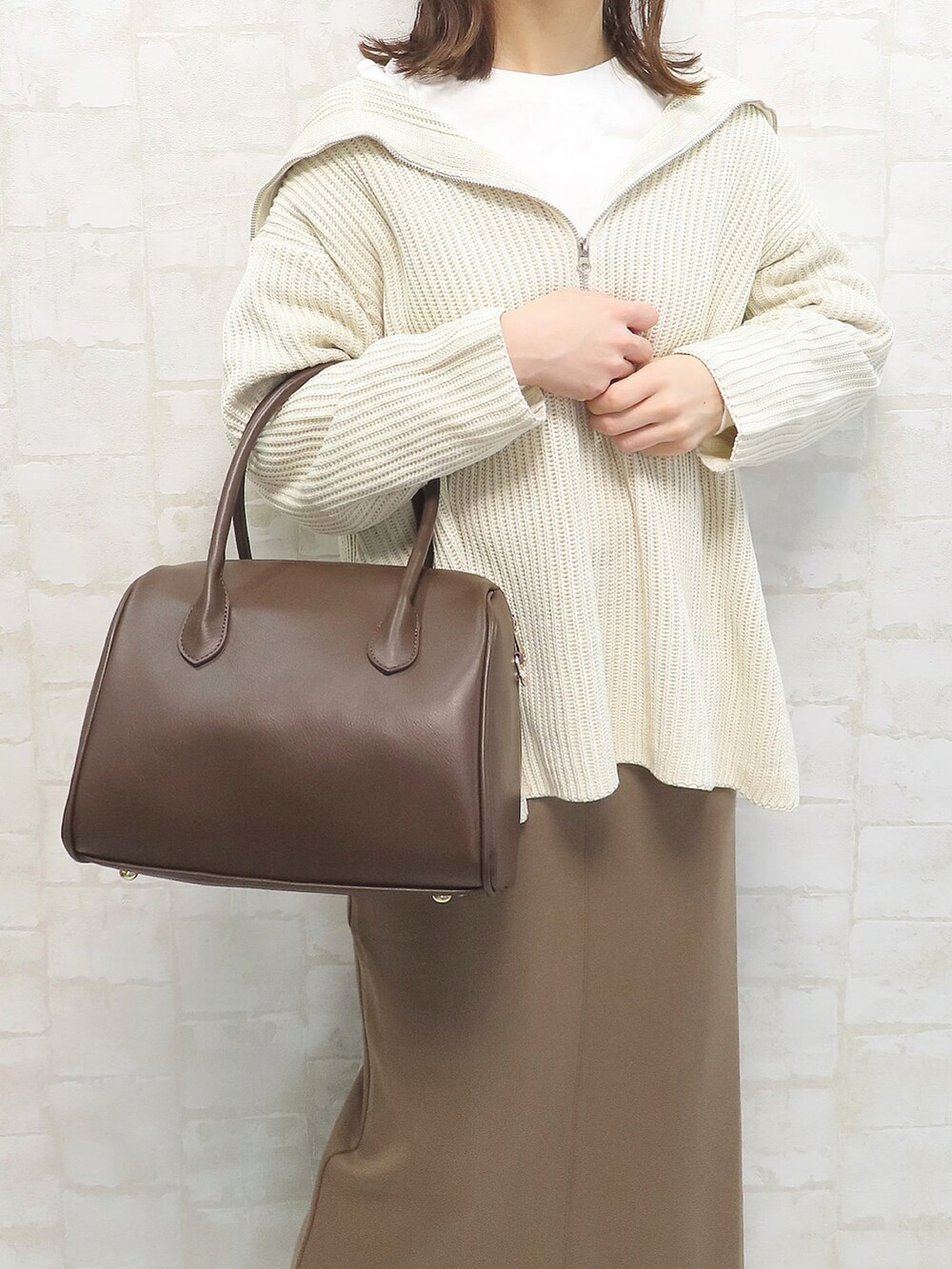 ホワイト系のニット/セーター、ブラウン系のボストンバッグ、ブラウン系のスカートを着用したレディースの冬コーディネートの3枚目の写真