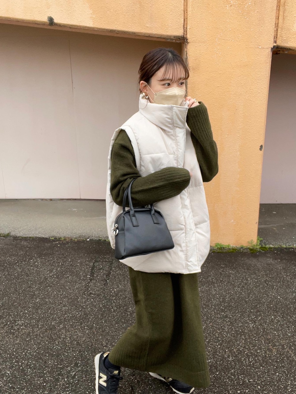 グリーン系のワンピース、ホワイト系のニット/セーター、ホワイト系のダウンベストを着用したレディースの冬コーディネートの2枚目の写真