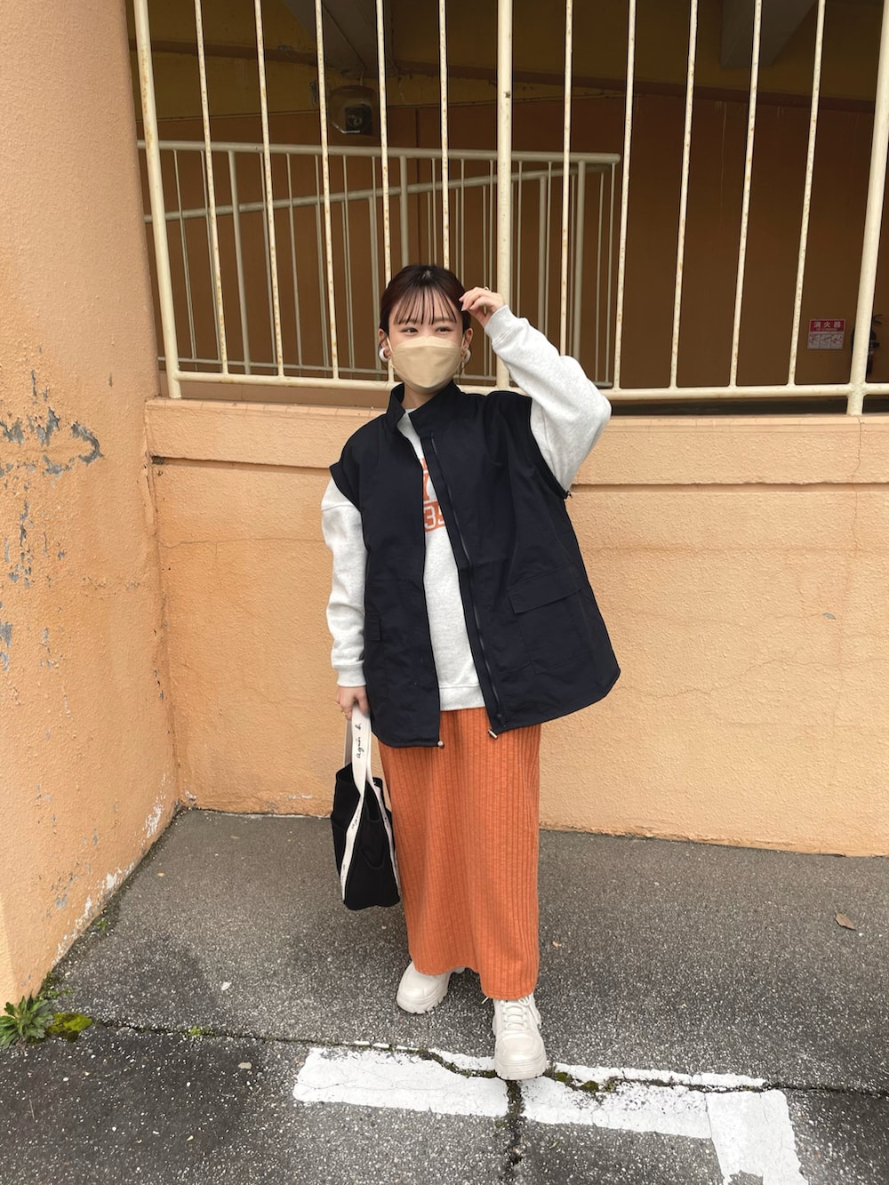 オレンジ系のスカート、ブラック系のマウンテンパーカー、グレー系のスウェットを着用したレディースの冬コーディネートの4枚目の写真