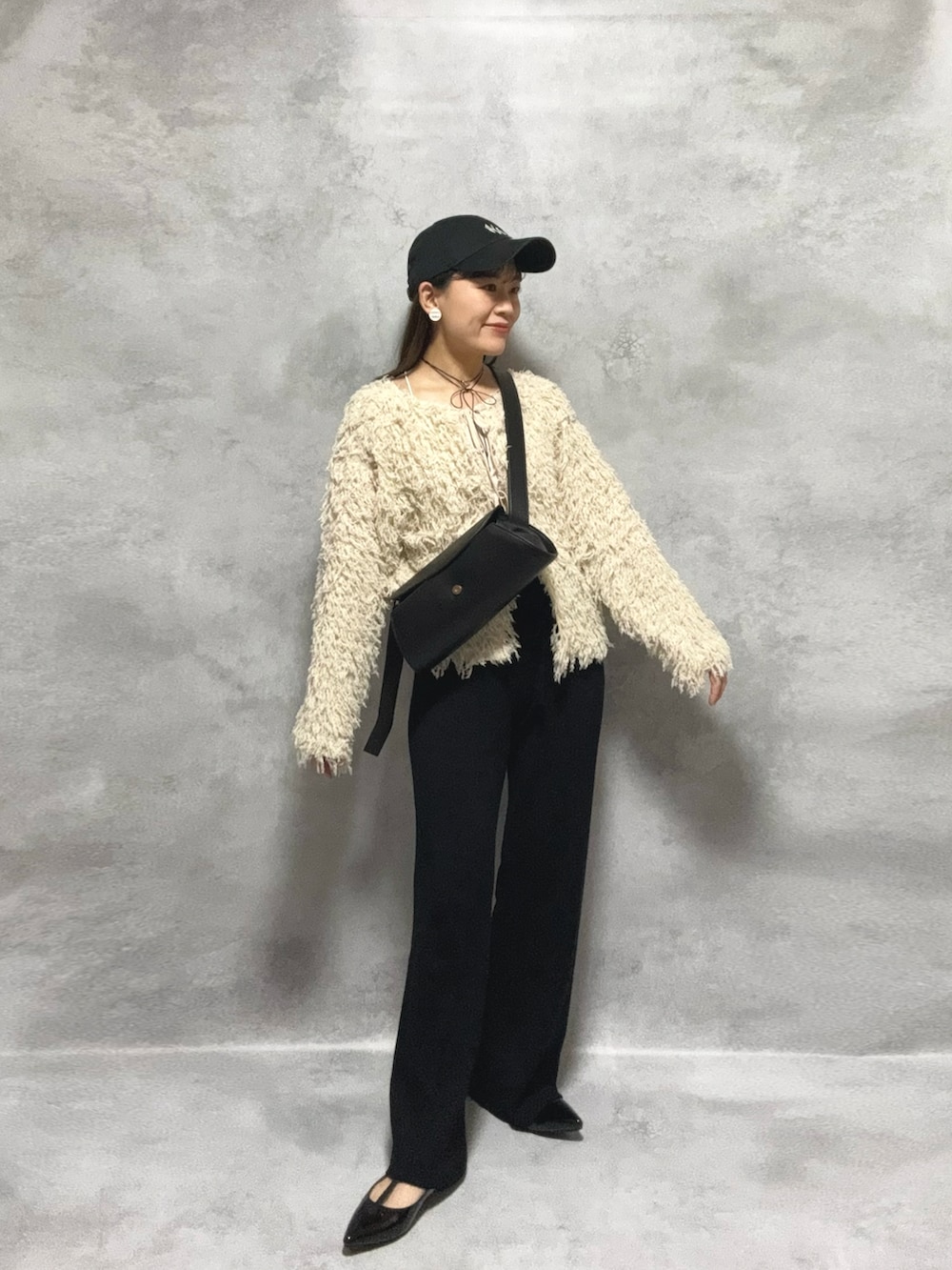 ホワイト系のカーディガン/ボレロ、ブラック系のパンツ、ブラック系のショルダーバッグを着用したレディースの秋コーディネートの2枚目の写真