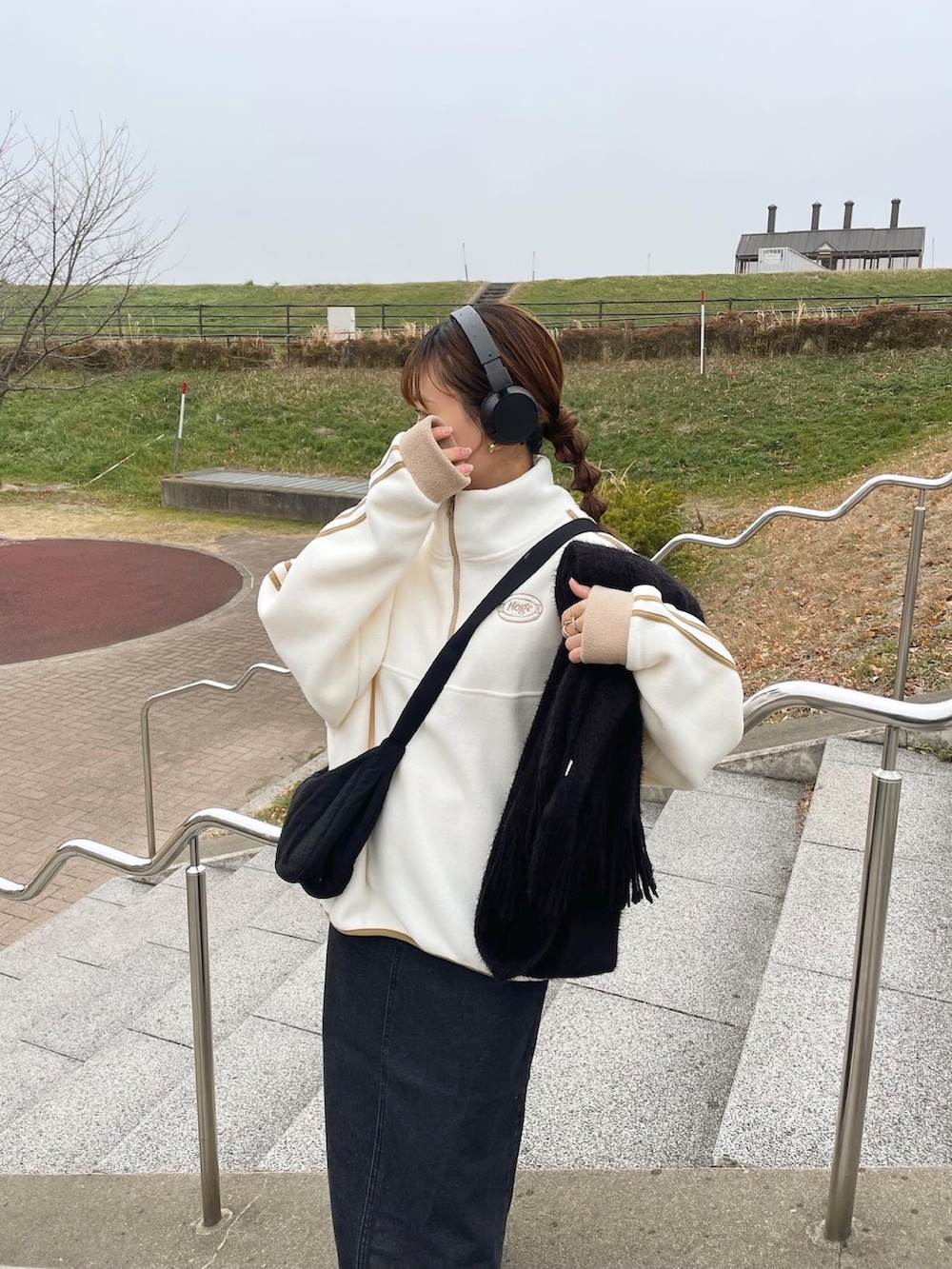 ブラック系のデニムスカート、ブラック系のショルダーバッグ、ホワイト系のスニーカーを着用したレディースの冬コーディネートの3枚目の写真