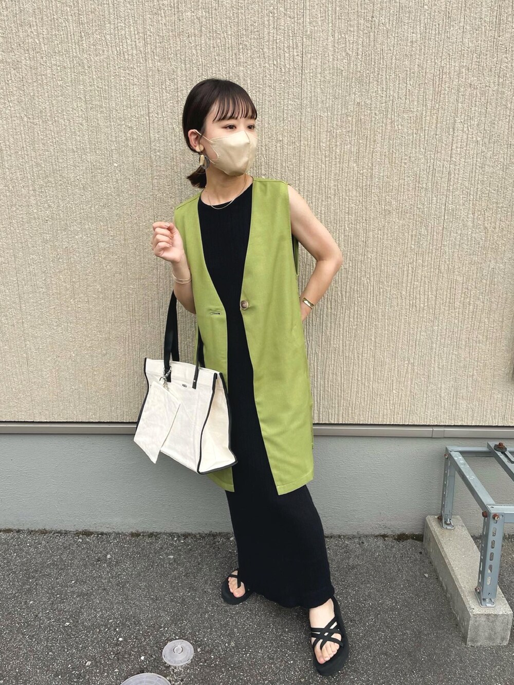 ホワイト系のトートバッグ、グリーン系のベスト、ブラック系のワンピースを着用したレディースの夏コーディネートの5枚目の写真