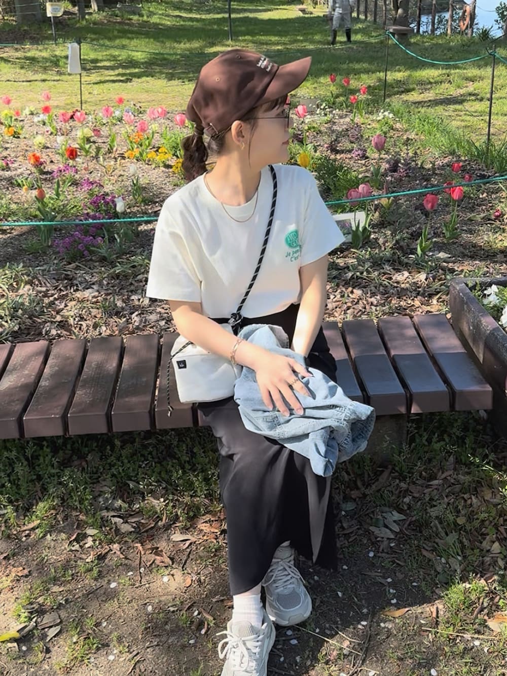ホワイト系のTシャツ/カットソー、ブラック系のスカート、ベージュ系のスニーカーを着用したレディースの夏コーディネートの3枚目の写真