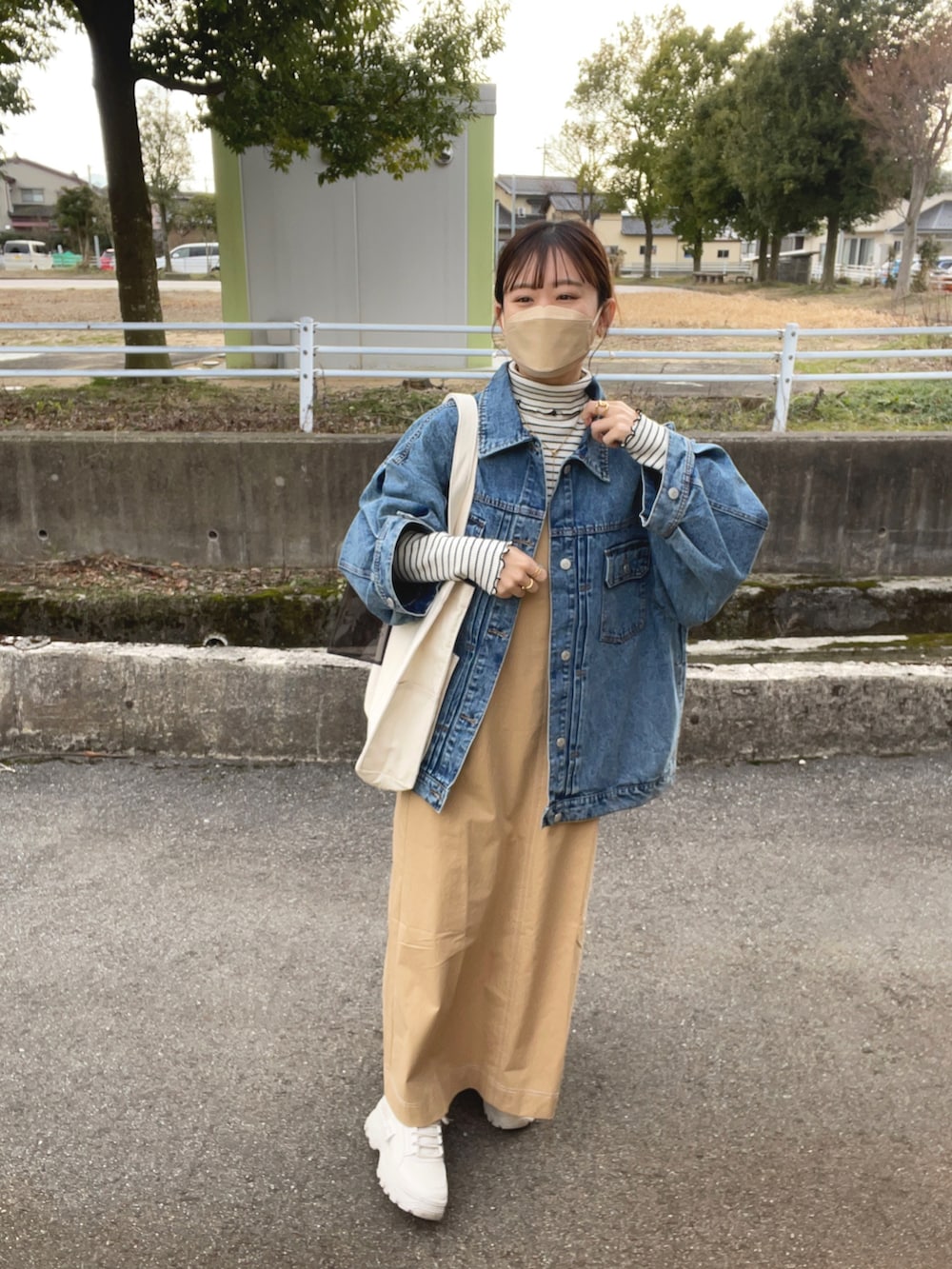 ベージュ系のワンピース、ホワイト系のトートバッグ、ブルー系のデニムジャケットを着用したレディースの春コーディネートの5枚目の写真