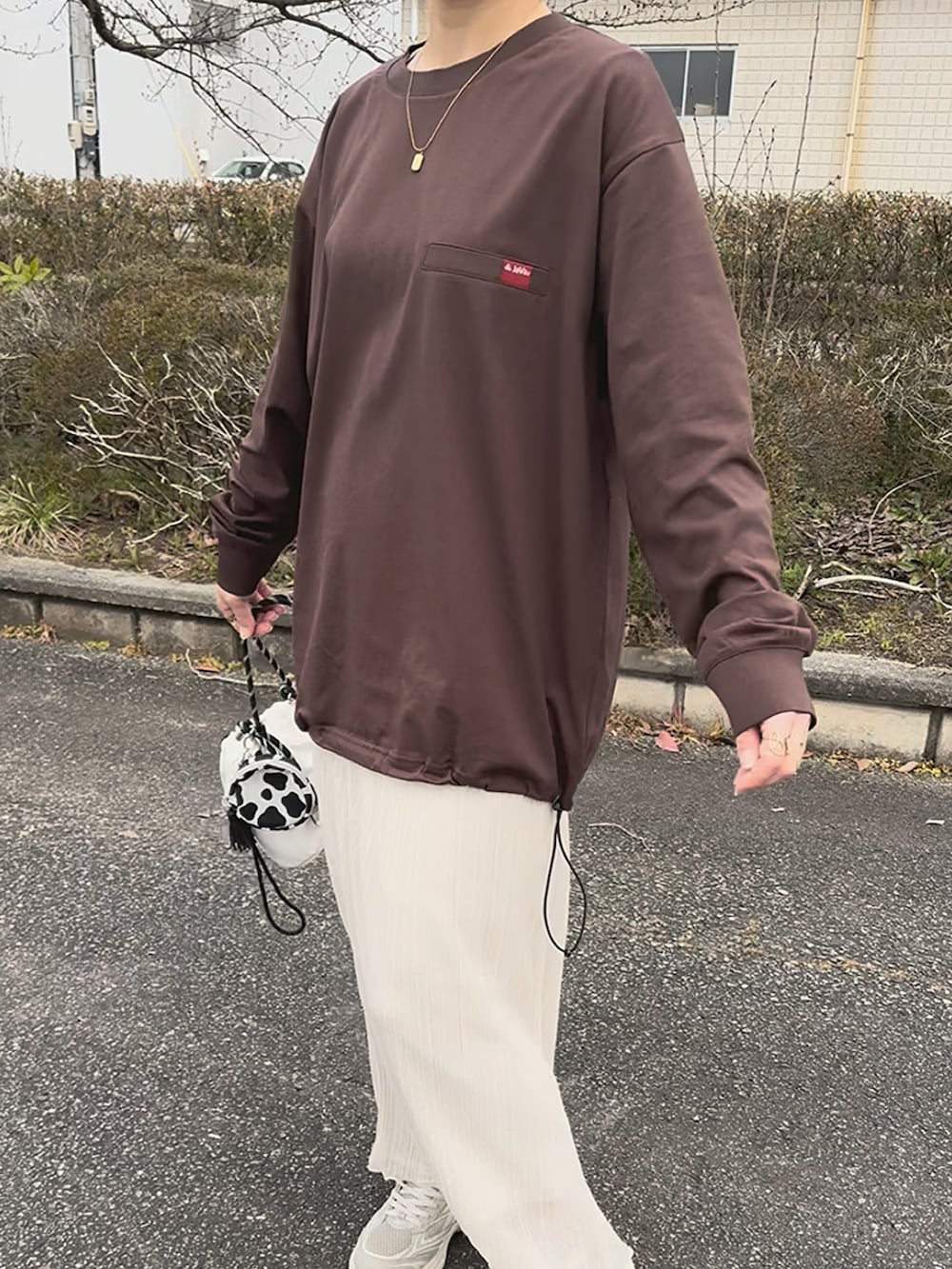 ブラウン系のTシャツ/カットソー、ホワイト系のスカート、ベージュ系のスニーカーを着用したレディースの春コーディネートの5枚目の写真
