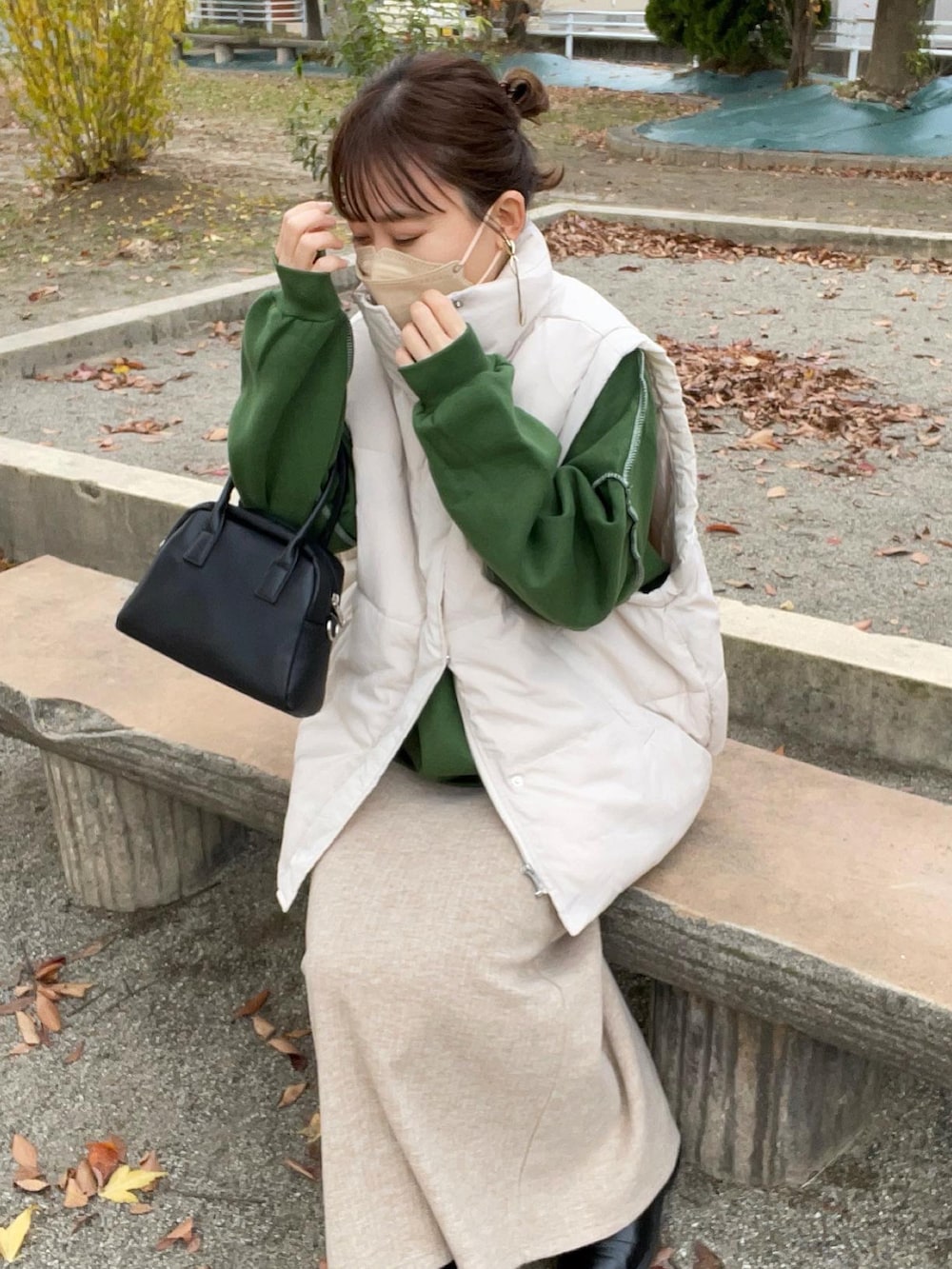 グリーン系のスウェット、ホワイト系のダウンベスト、ブラック系のボストンバッグを着用したレディースの秋コーディネートの4枚目の写真