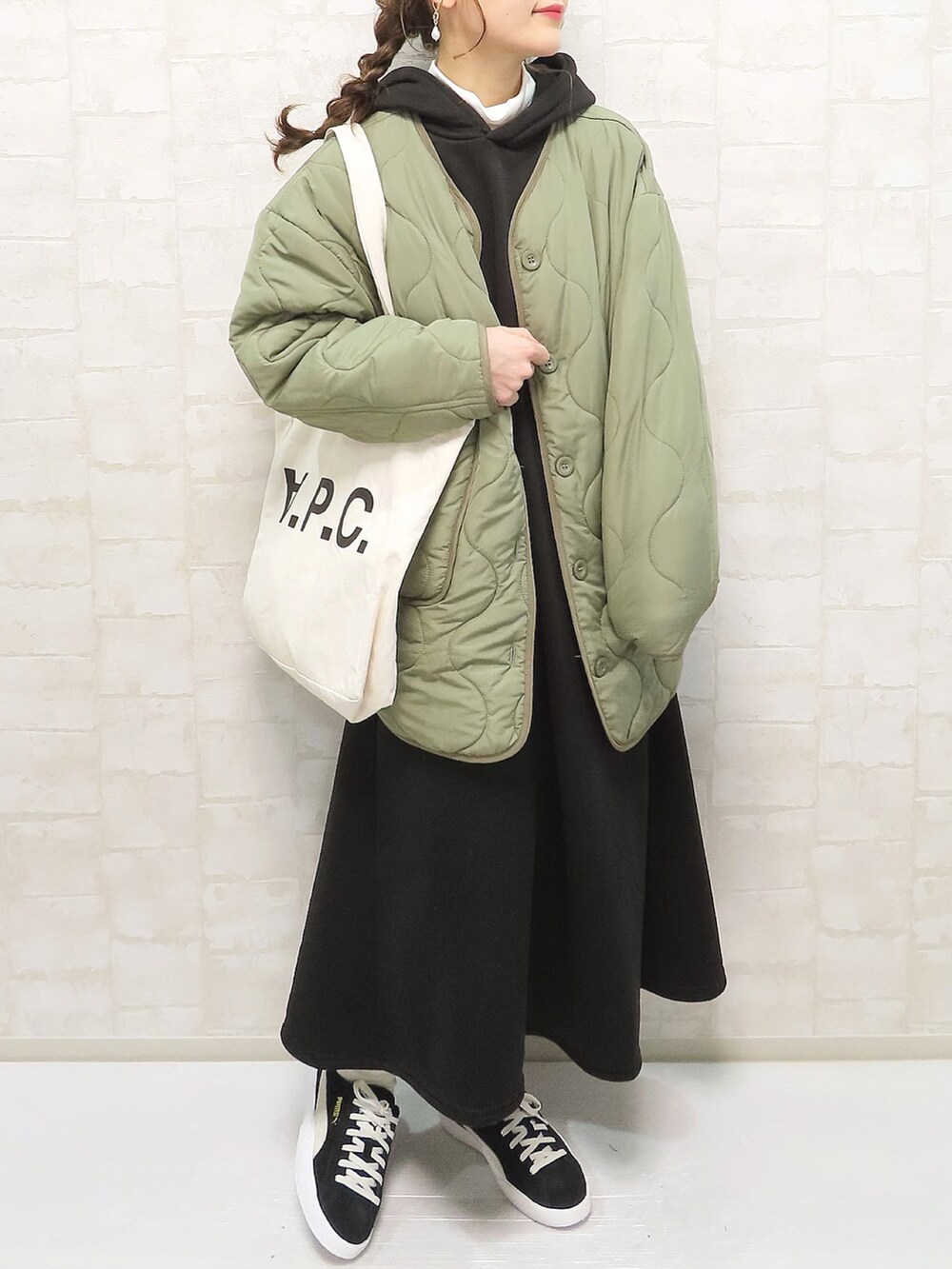 ブラック系のワンピース、ホワイト系のトップス、グリーン系のノーカラージャケットを着用したレディースの冬コーディネートの3枚目の写真