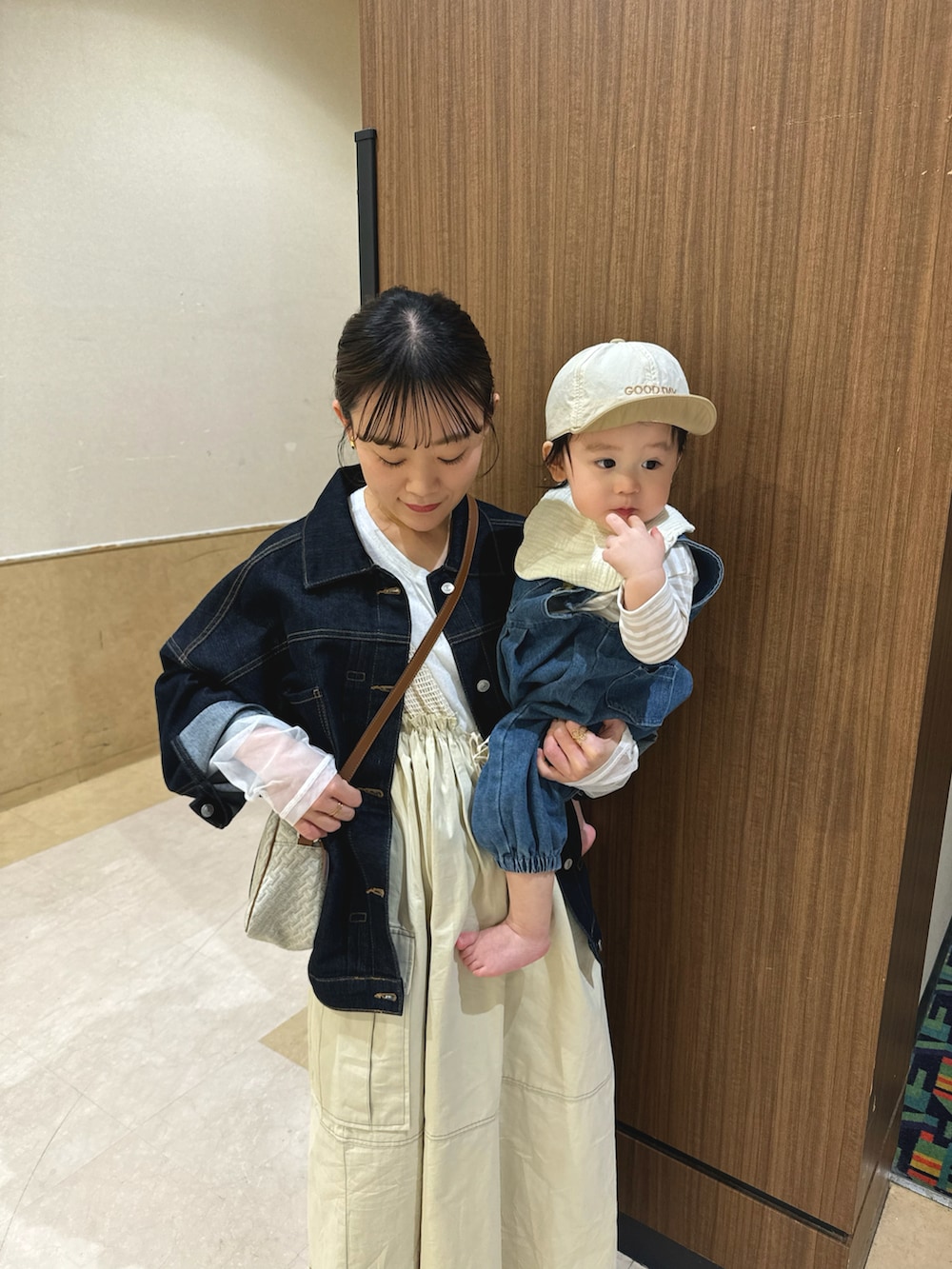 ベージュ系のワンピース、ブルー系のデニムジャケット、ホワイト系のショルダーバッグを着用したレディースの春コーディネートの4枚目の写真