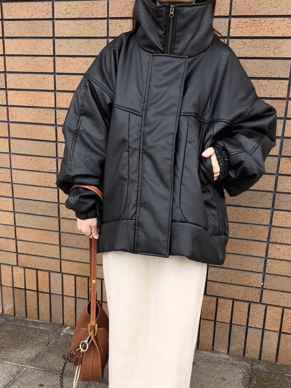 ブラック系のブルゾン、ホワイト系のワンピース、ブラウン系のショルダーバッグを着用したレディースの冬コーディネートの5枚目の写真