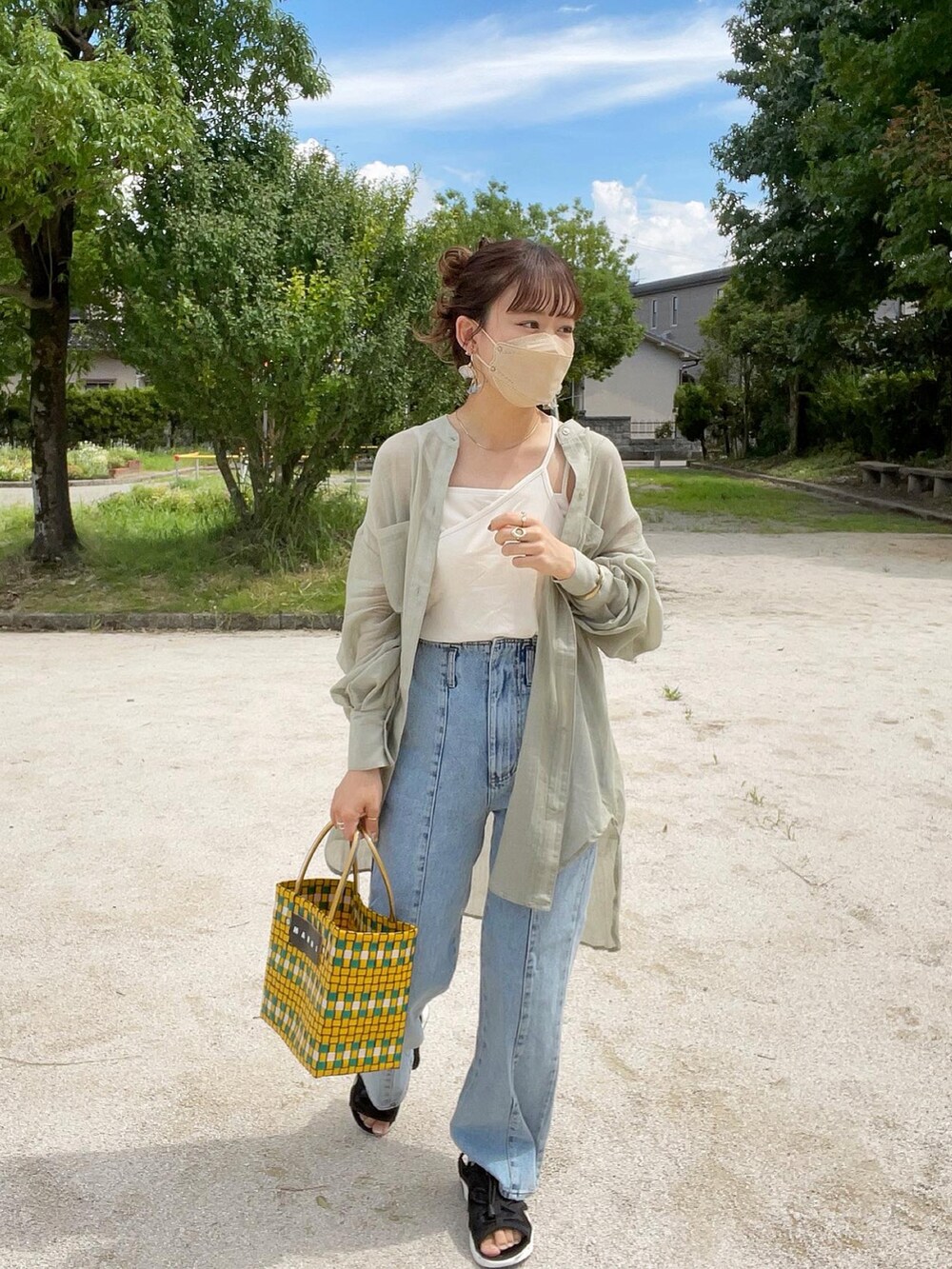 グリーン系のシャツ/ブラウス、ホワイト系のキャミソール、ブルー系のデニムパンツを着用したレディースの夏コーディネートの4枚目の写真