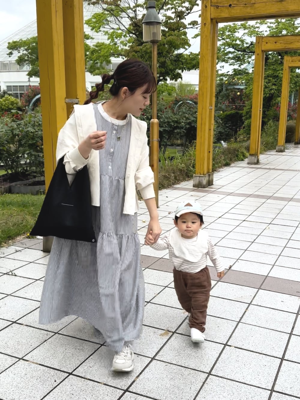 ブラック系のワンピース、ブラック系のトートバッグ、ホワイト系のスニーカーを着用したレディースの夏コーディネートの3枚目の写真