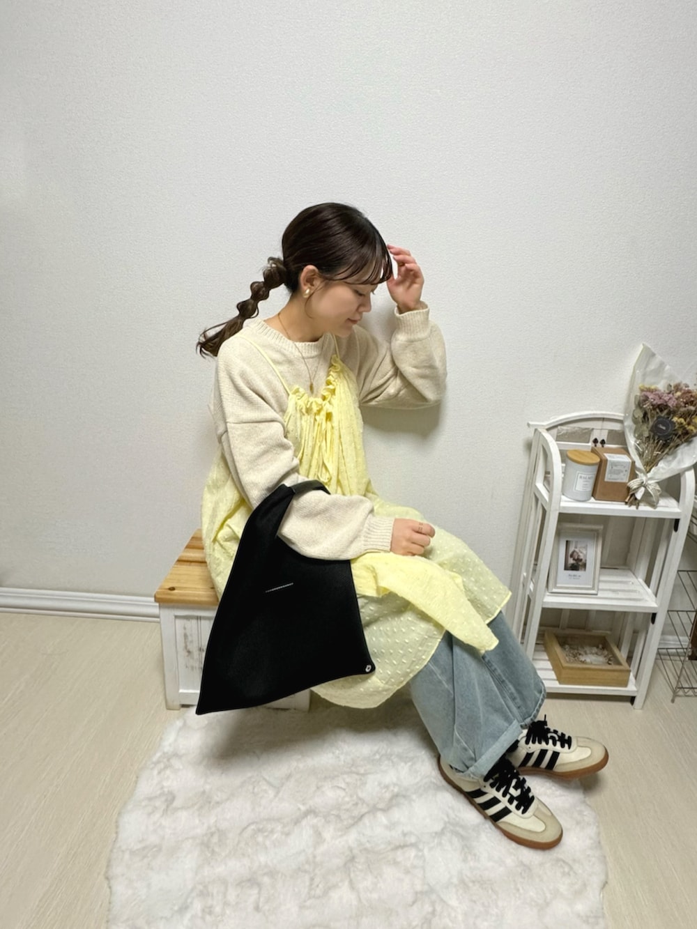 イエロー系のワンピース、ブルー系のデニムパンツ、ベージュ系のスニーカーを着用したレディースの冬コーディネートの2枚目の写真