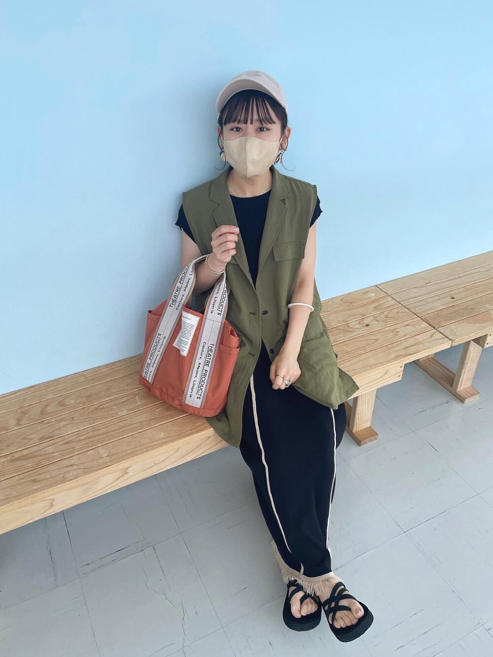 ブラック系のワンピース、グリーン系のベスト、オレンジ系のトートバッグを着用したレディースの夏コーディネートの3枚目の写真