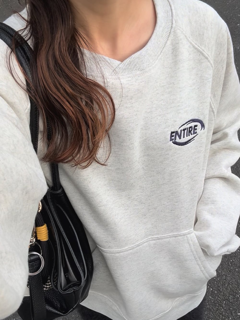 ベージュ系のスウェット、ホワイト系のスニーカー、ブラック系のスカートを着用したレディースの秋コーディネートの2枚目の写真