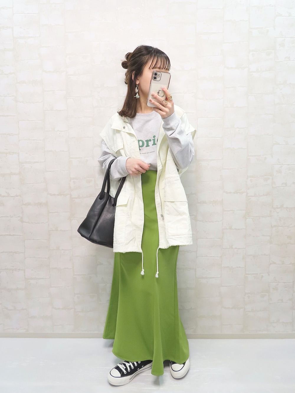 グレー系のTシャツ/カットソー、ホワイト系のベスト、グリーン系のスカートを着用したレディースの春コーディネートの2枚目の写真