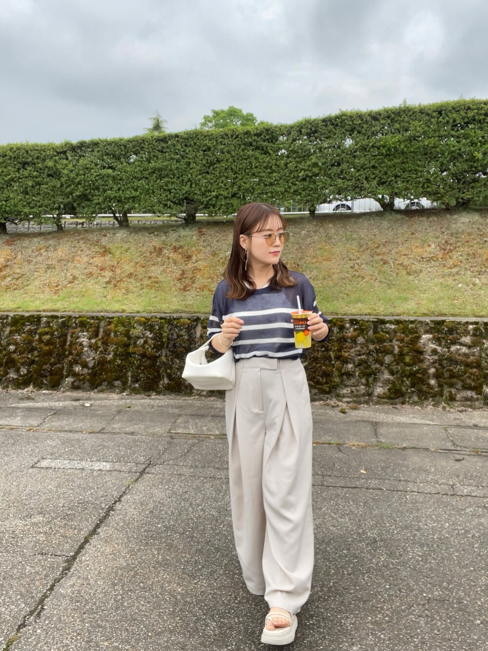 ブルー系のTシャツ/カットソー、ホワイト系のスラックス、ホワイト系のハンドバッグを着用したレディースの夏コーディネートの2枚目の写真