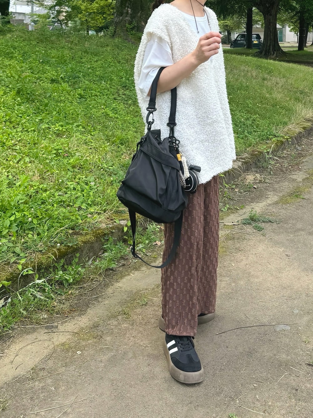 ブラウン系のスカート、ホワイト系のトップス、ブラック系のバッグを着用したレディースの夏コーディネートの2枚目の写真