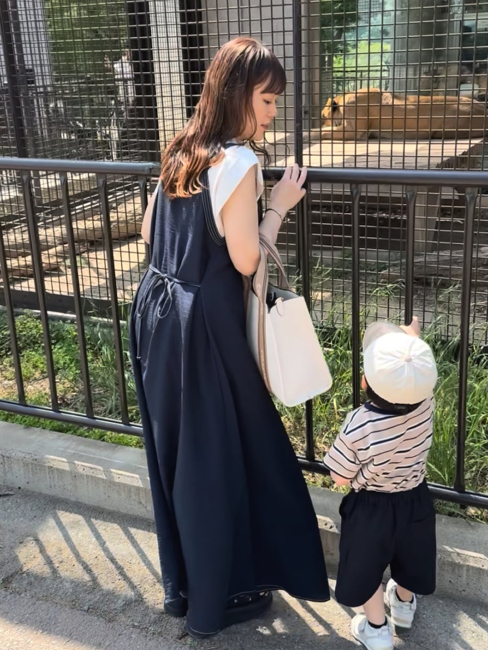 ブルー系のワンピース、ベージュ系のバッグ、ブラック系のサンダルを着用したレディースの夏コーディネートの2枚目の写真