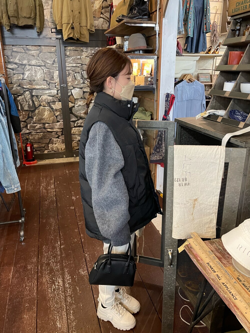 グレー系のニット/セーター、ブラック系のダウンベスト、ホワイト系のパンツを着用したレディースの冬コーディネートの5枚目の写真