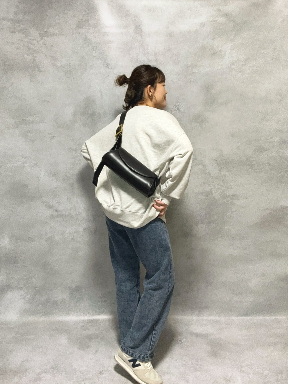 グレー系のスウェット、ブラック系のショルダーバッグ、ブラック系のスカートを着用したレディースの秋コーディネートの2枚目の写真