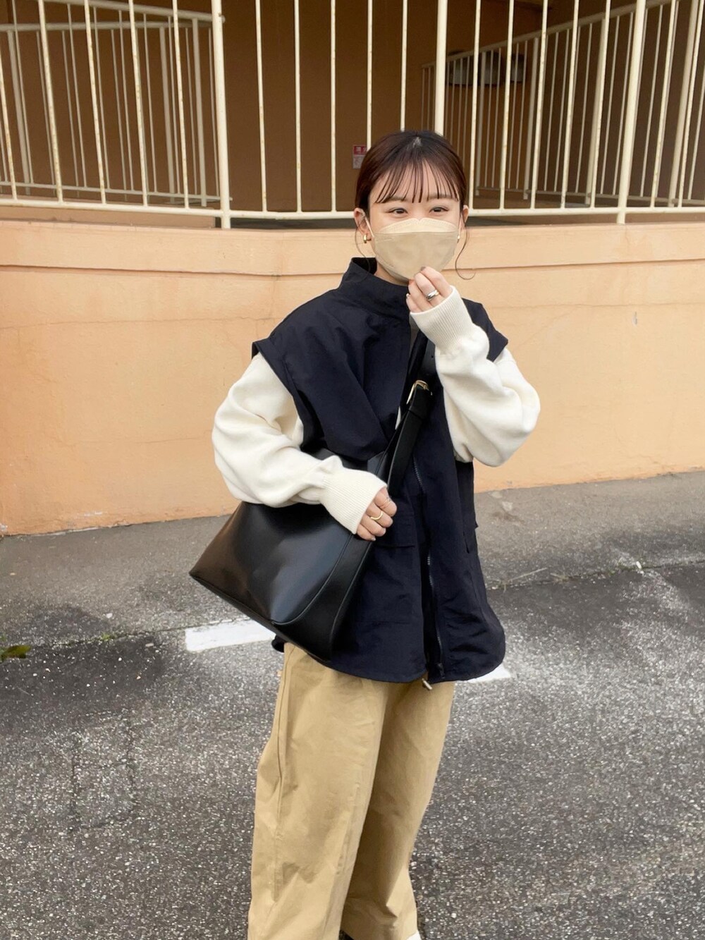 ベージュ系のその他パンツ、ホワイト系のニット/セーター、ブラック系のマウンテンパーカーを着用したレディースの春コーディネートの2枚目の写真