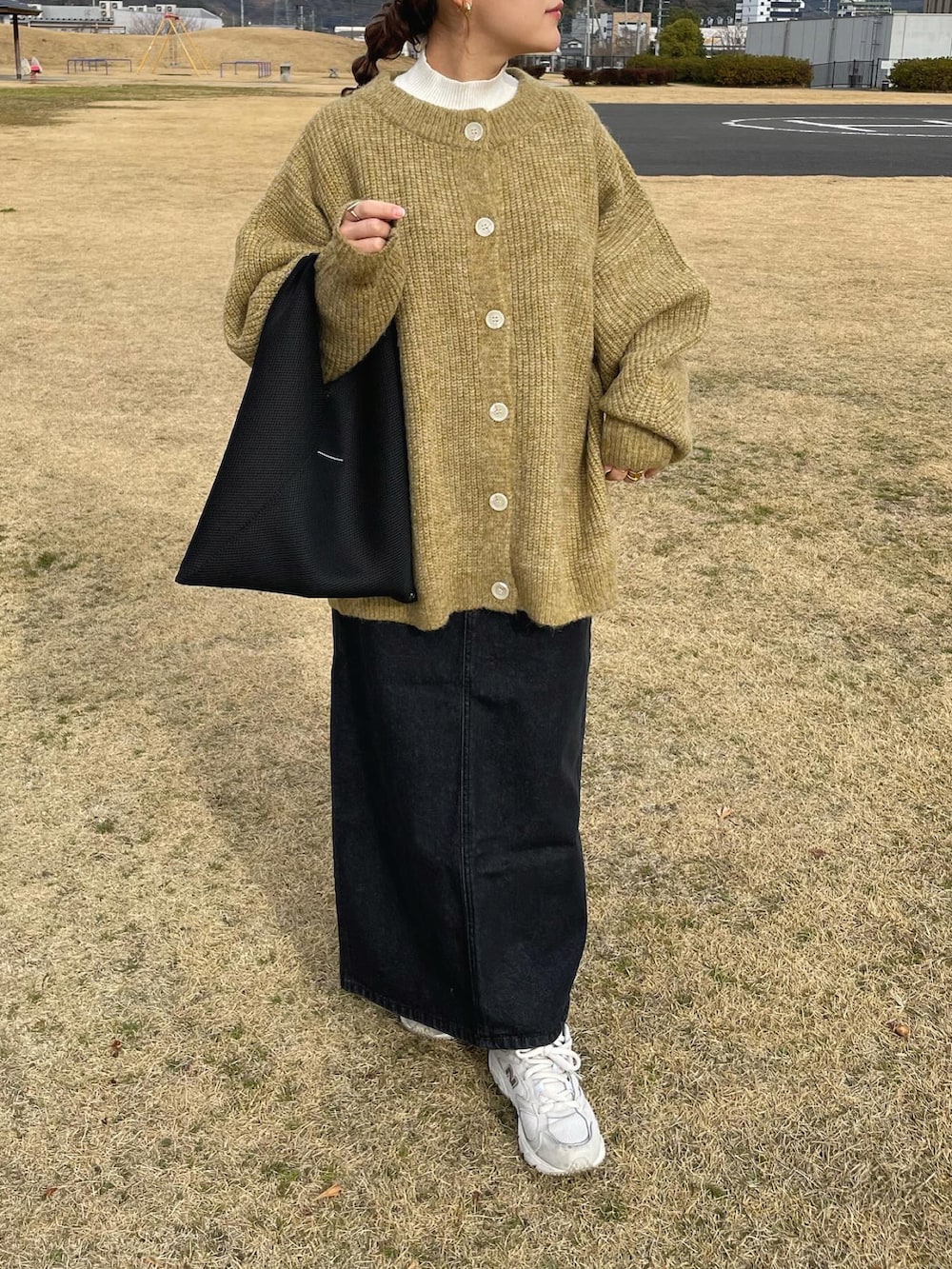 グリーン系のニット/セーター、ブラック系のデニムスカート、ブラック系のトートバッグを着用したレディースの冬コーディネートの4枚目の写真