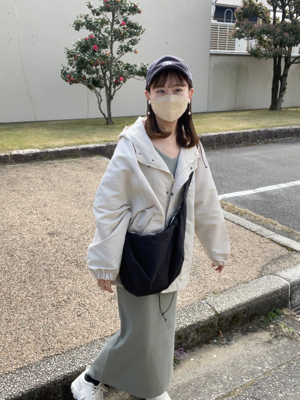 ホワイト系のマウンテンパーカー、グリーン系のワンピース/ドレス、ホワイト系のスニーカーを着用したレディースの春コーディネートの4枚目の写真