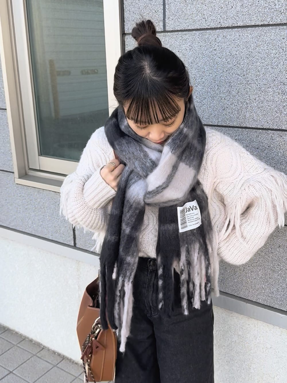 ブラウン系のショルダーバッグ、ホワイト系のニット/セーター、ブルー系のパンツを着用したレディースの冬コーディネートの3枚目の写真