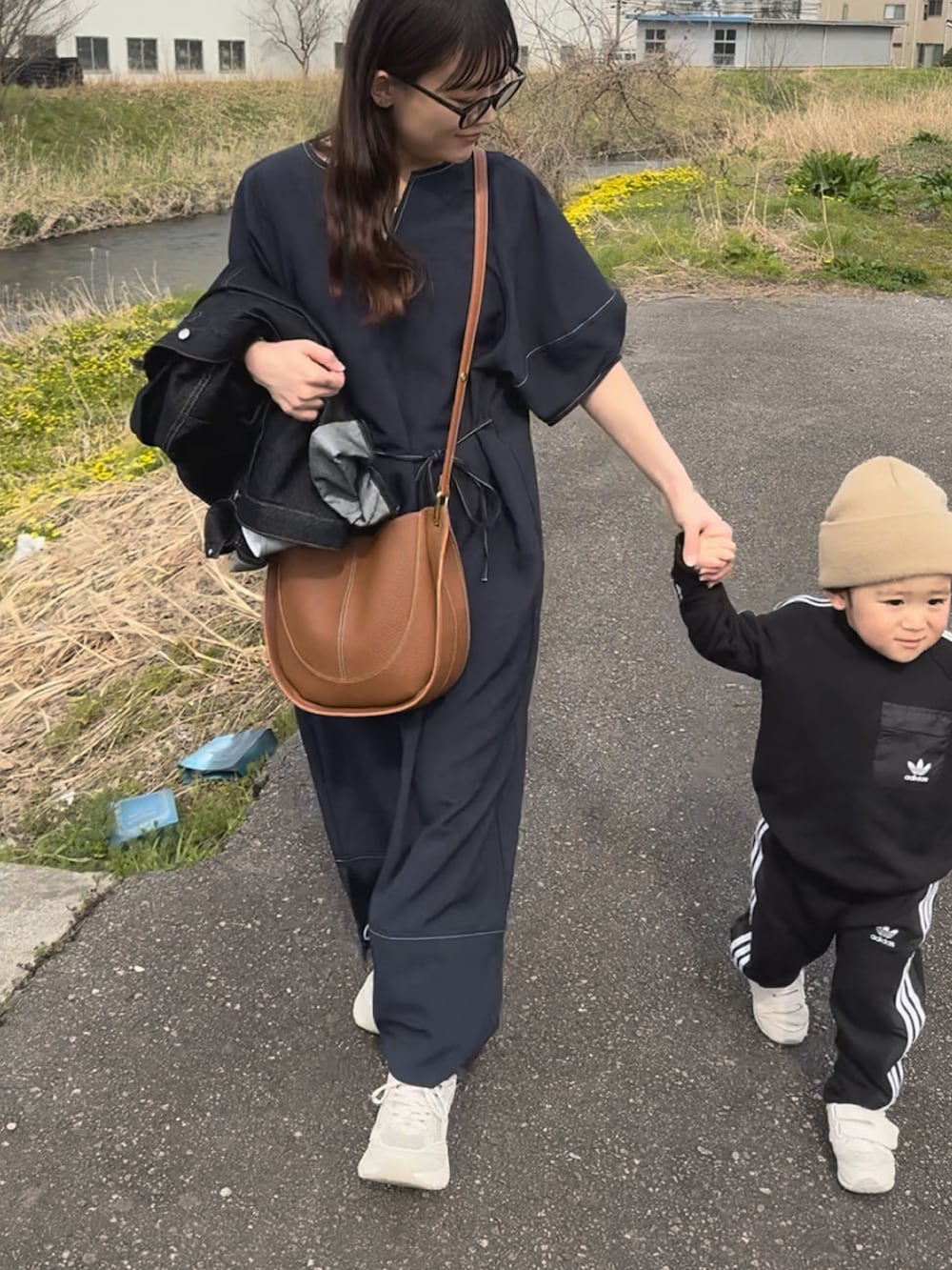 ブルー系のワンピース、ブルー系のデニムジャケット、ブラウン系のショルダーバッグを着用したレディースの春コーディネートの2枚目の写真