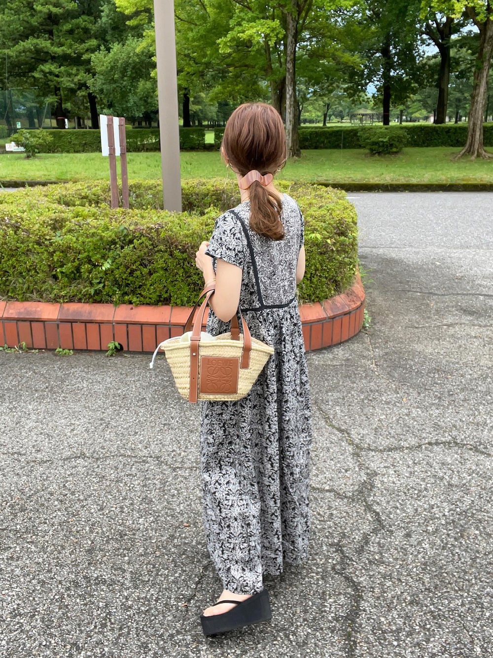 ブラック系のワンピース、ベージュ系のかごバッグ、ブラック系のサンダルを着用したレディースの夏コーディネートの5枚目の写真