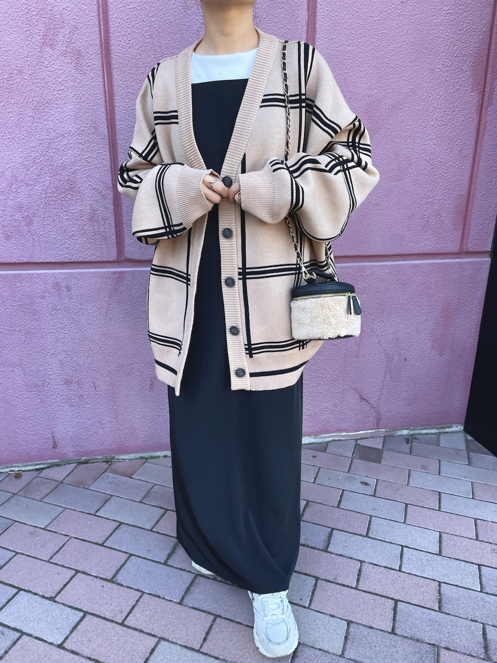 ベージュ系のカーディガン/ボレロ、ブラック系のワンピース、ホワイト系のスニーカーを着用したレディースの冬コーディネートの5枚目の写真