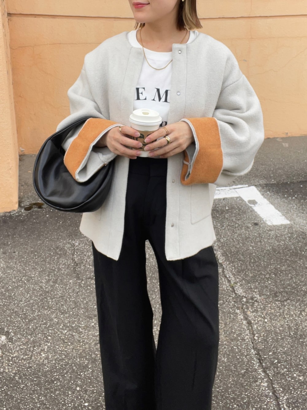 ベージュ系のノーカラーコート、ホワイト系のTシャツ/カットソー、ブラック系のパンツを着用したレディースの秋コーディネートの3枚目の写真