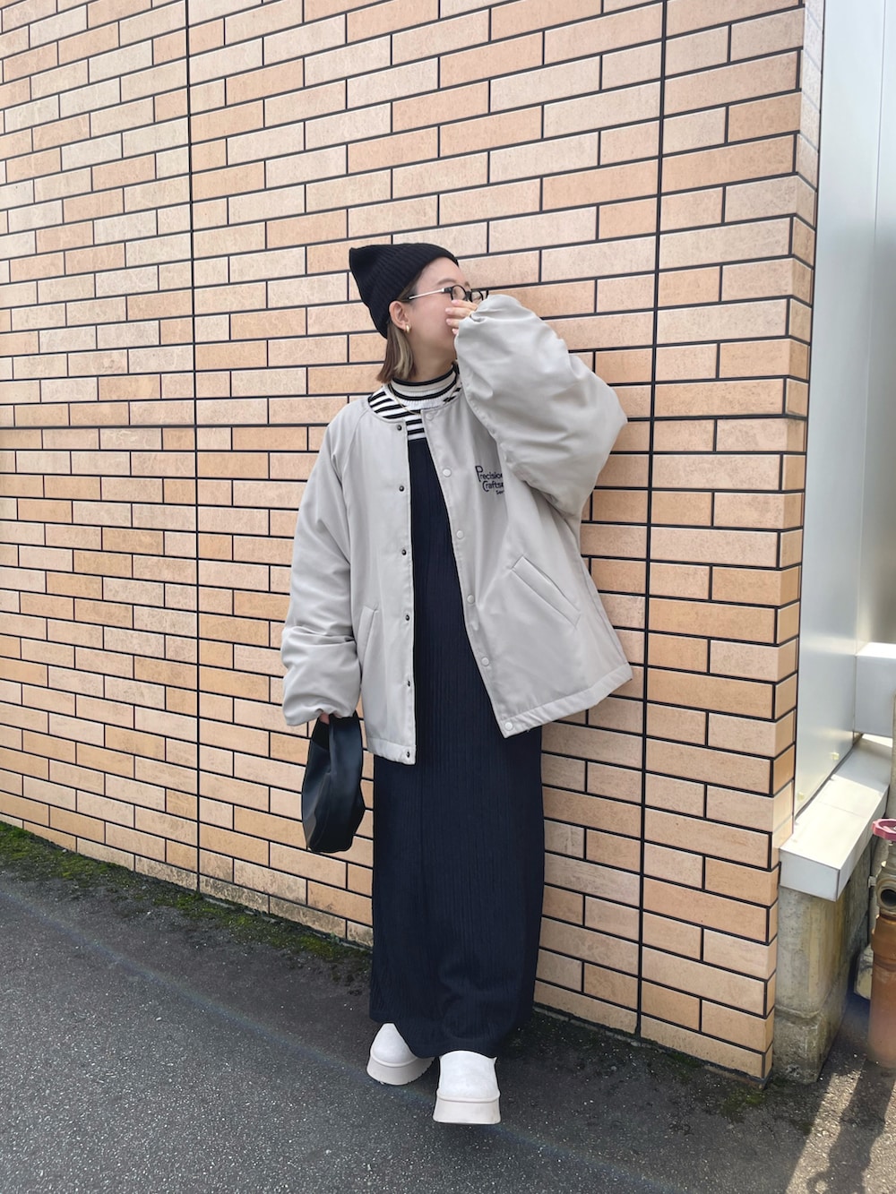 ベージュ系のブルゾン、ブラック系のワンピース/ドレス、ベージュ系のブーツを着用したレディースの冬コーディネートの3枚目の写真