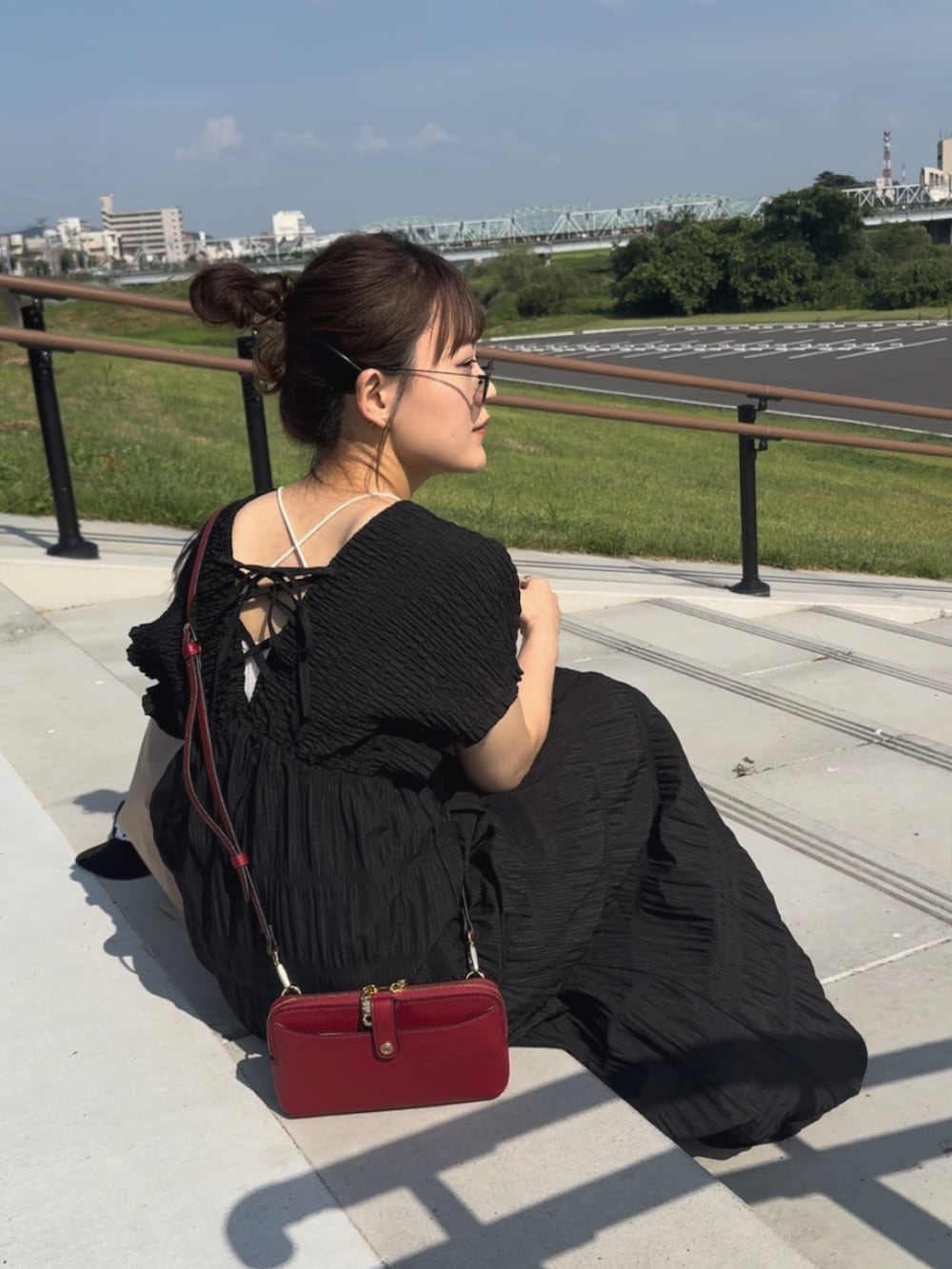 ブラック系のワンピース、ブラック系のサンダル、レッド系のショルダーバッグを着用したレディースの夏コーディネートの3枚目の写真