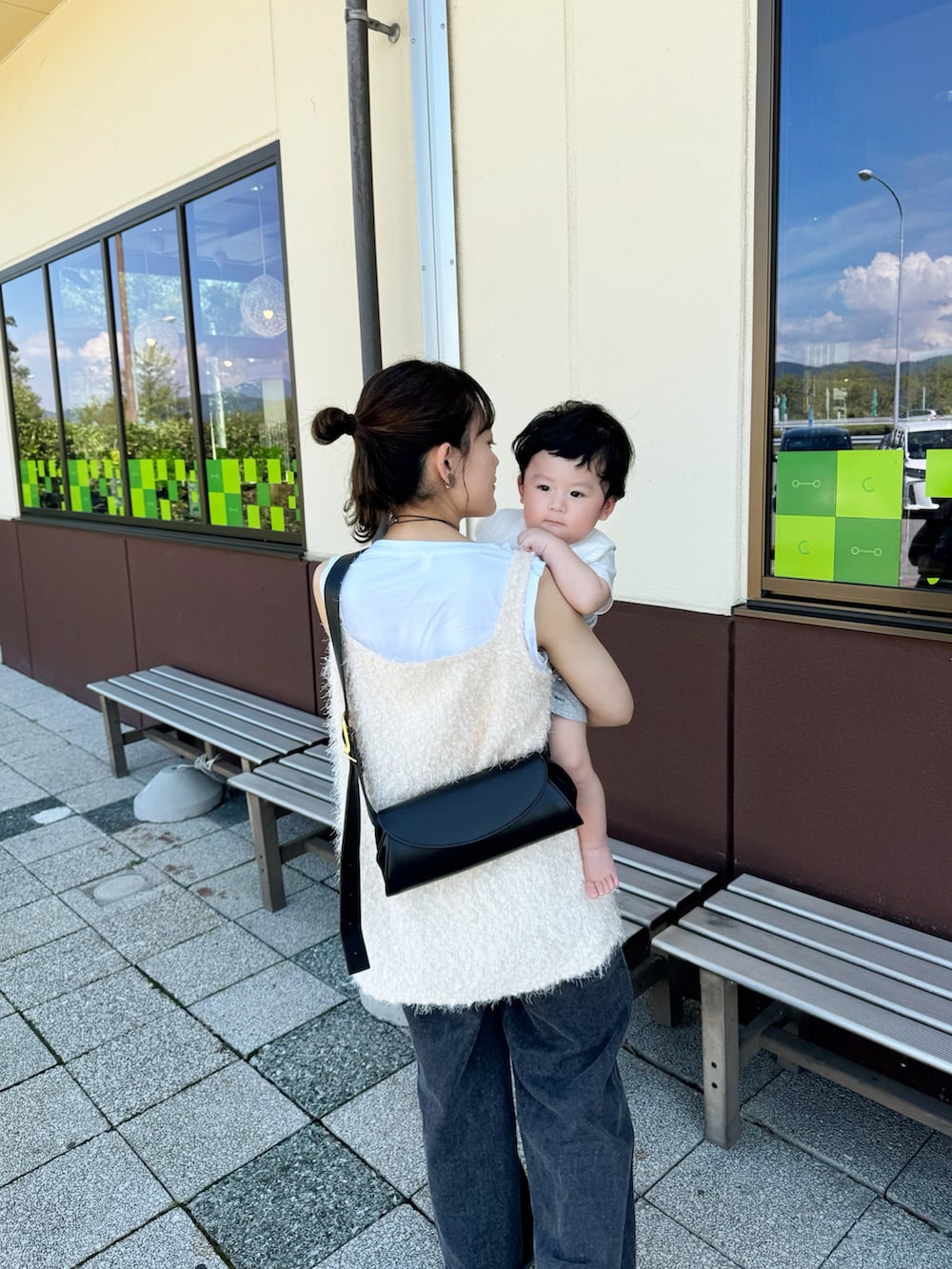 ホワイト系のベスト、ブラック系のショルダーバッグ、ブラック系のデニムパンツを着用したレディースの秋コーディネートの3枚目の写真