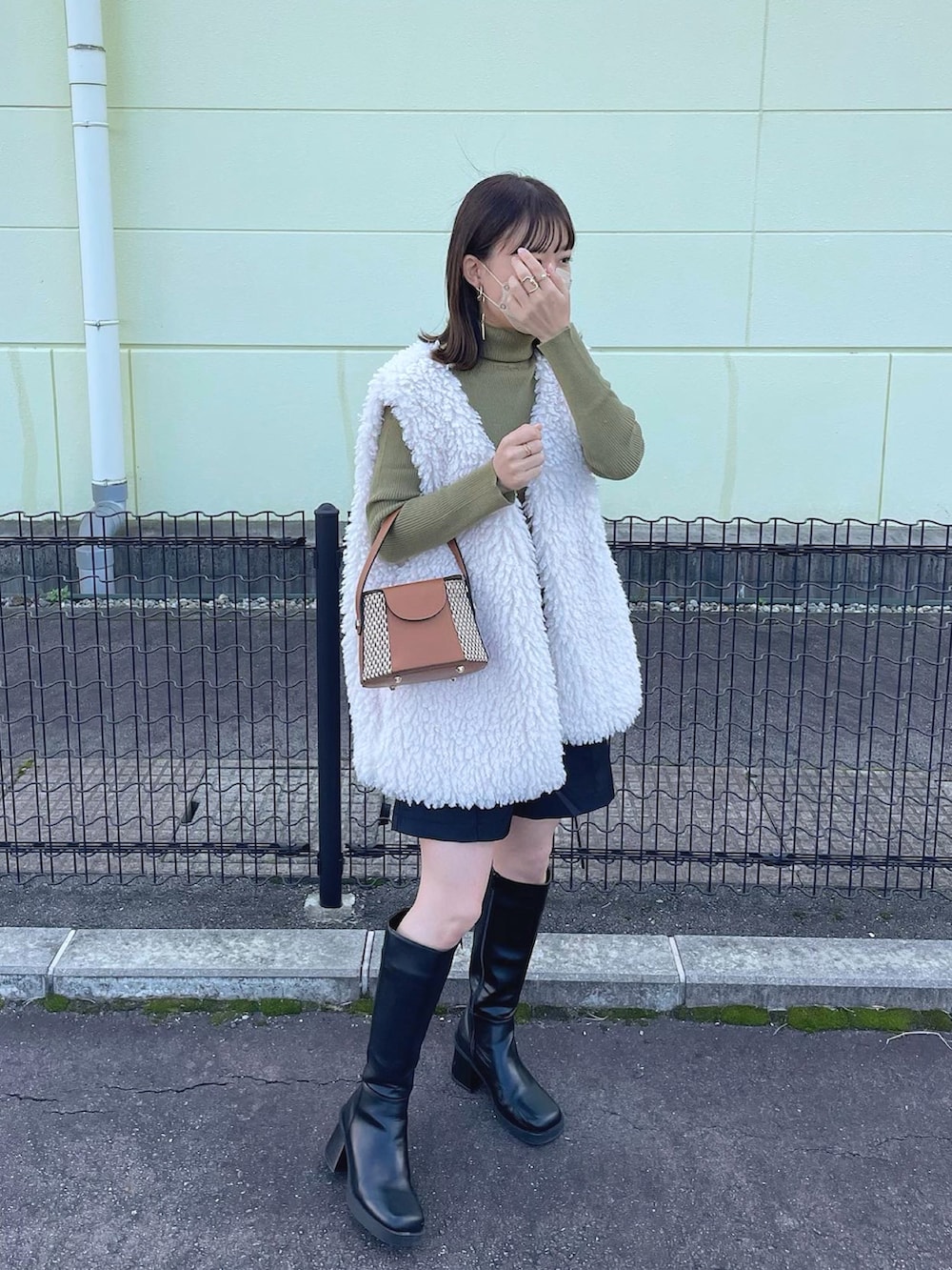 ホワイト系のベスト、グリーン系のニット/セーター、ブラック系のスラックスを着用したレディースの秋コーディネートの4枚目の写真