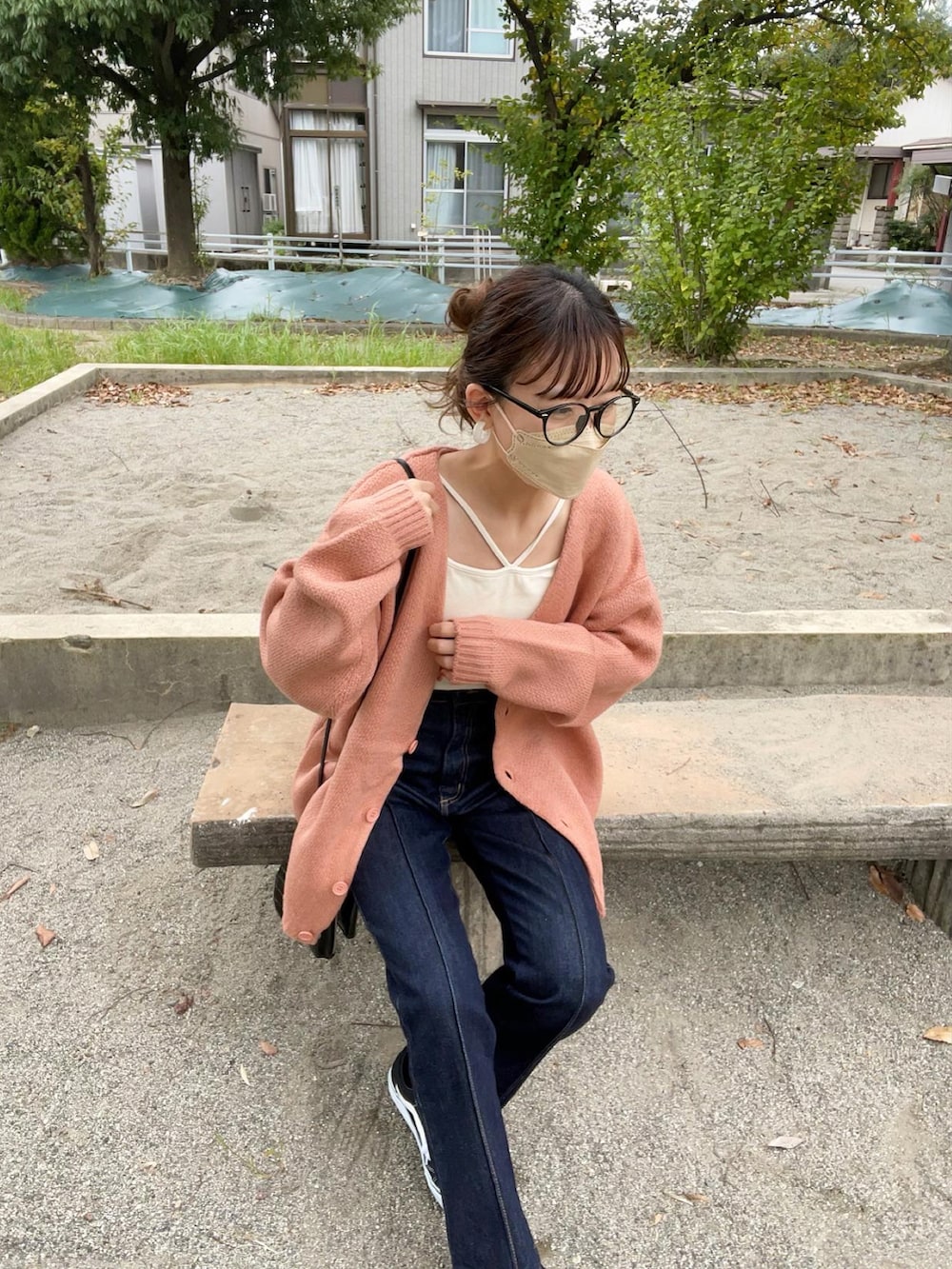 ピンク系のカーディガン/ボレロ、ホワイト系のキャミソール、ブラック系のデニムパンツを着用したレディースの秋コーディネートの2枚目の写真