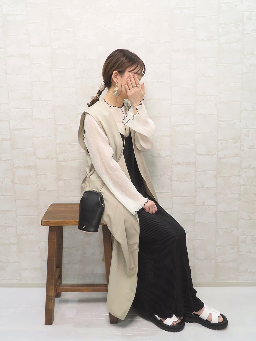 ベージュ系のベスト、ホワイト系のTシャツ/カットソー、ブラック系のワンピース/ドレスを着用したレディースの春コーディネートの2枚目の写真