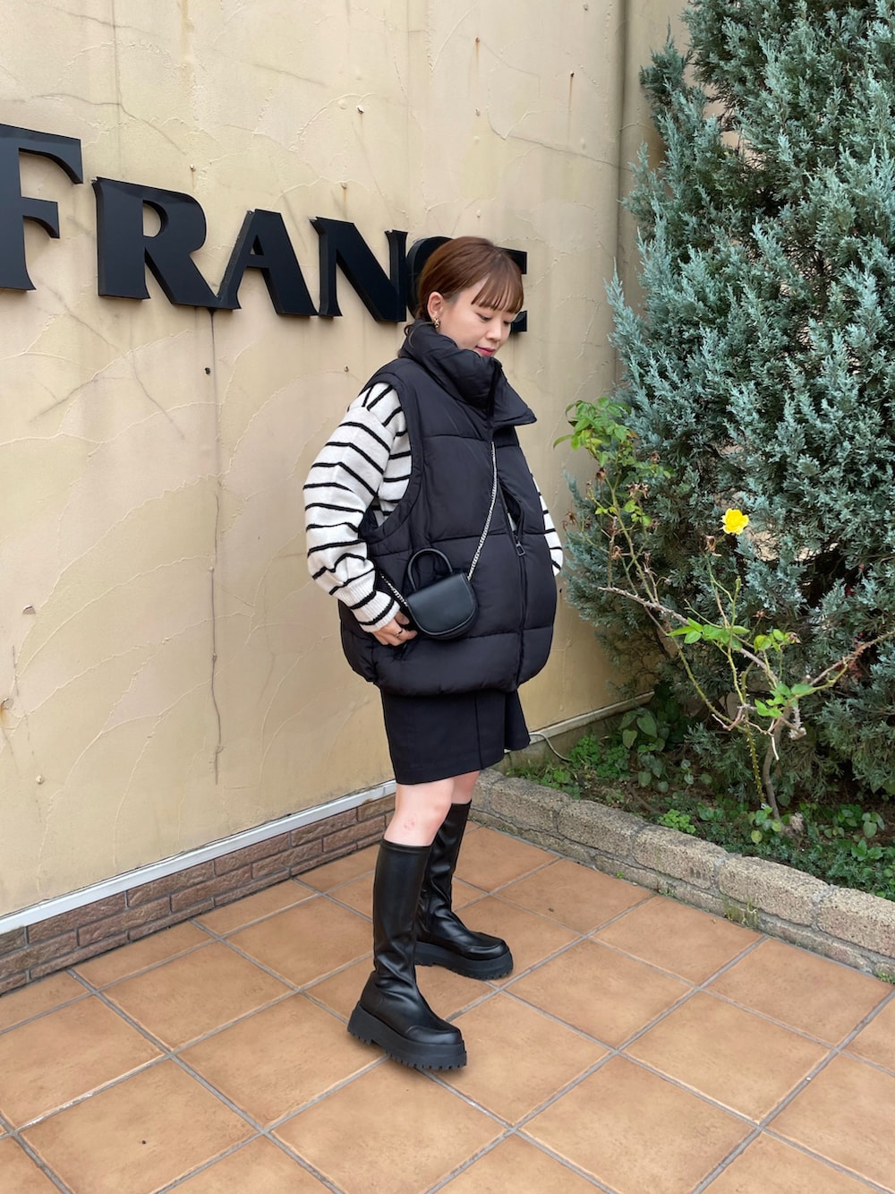 ブラック系のベスト、ブラック系のショルダーバッグ、ホワイト系のニット/セーターを着用したレディースの秋コーディネートの3枚目の写真