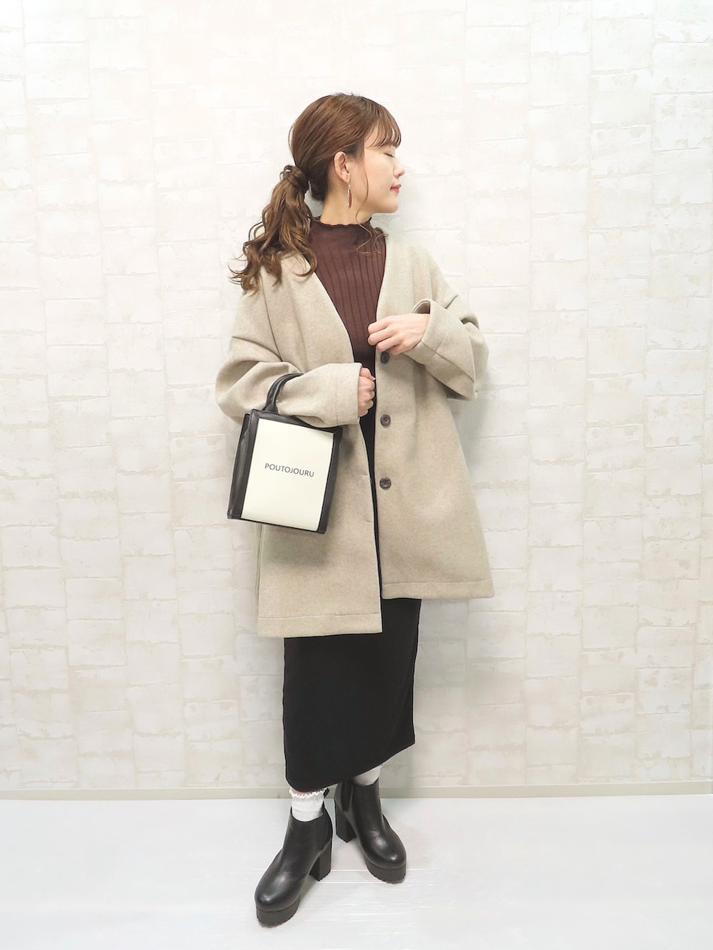 ベージュ系のノーカラーコート、ホワイト系のトートバッグ、ブラウン系のニット/セーターを着用したレディースの秋コーディネートの2枚目の写真