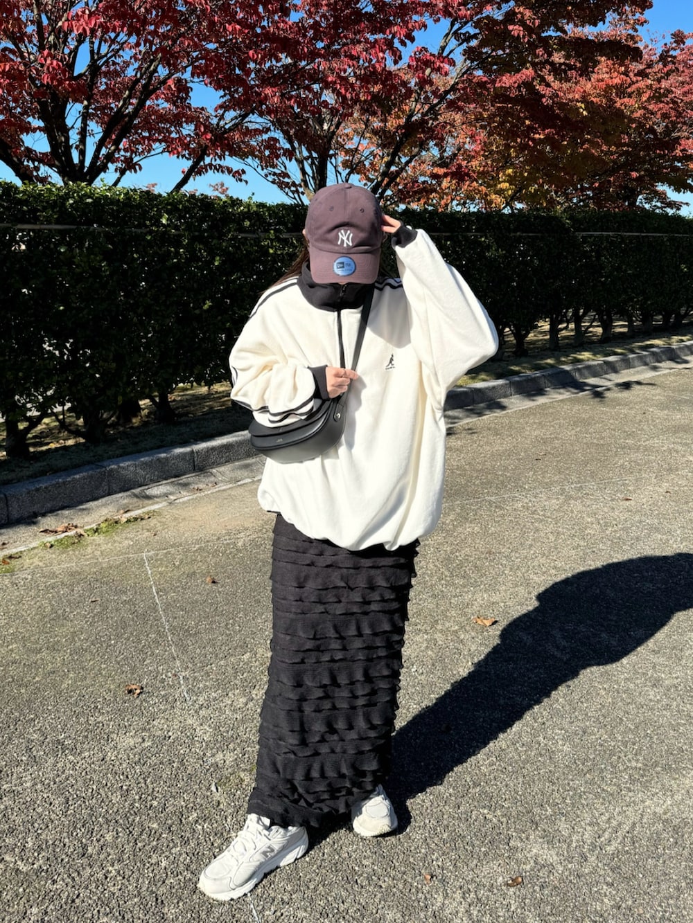 ホワイト系のスウェット、ブラック系のスカート、ホワイト系のスニーカーを着用したレディースの秋コーディネートの3枚目の写真