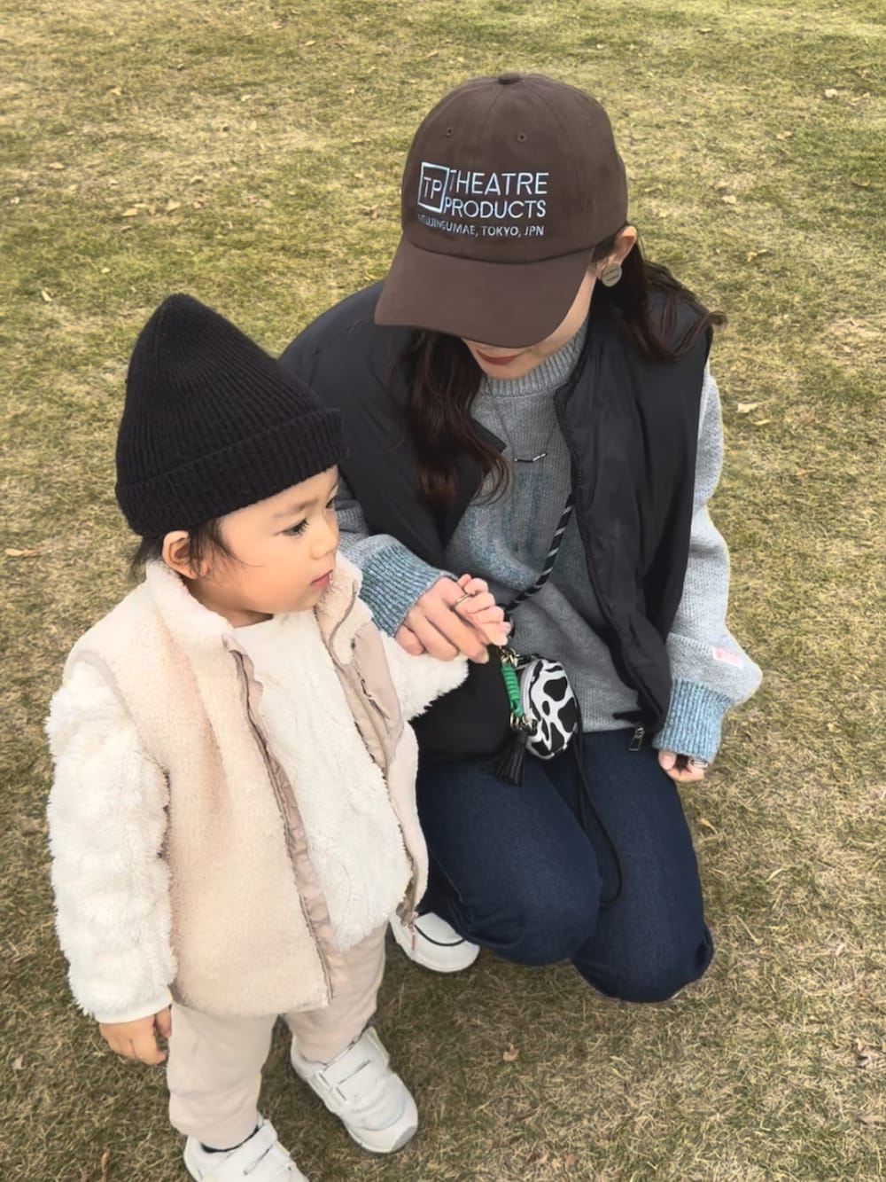 グレー系のニット/セーター、ブルー系のデニムパンツ、ブラック系のスニーカーを着用したレディースの冬コーディネートの3枚目の写真