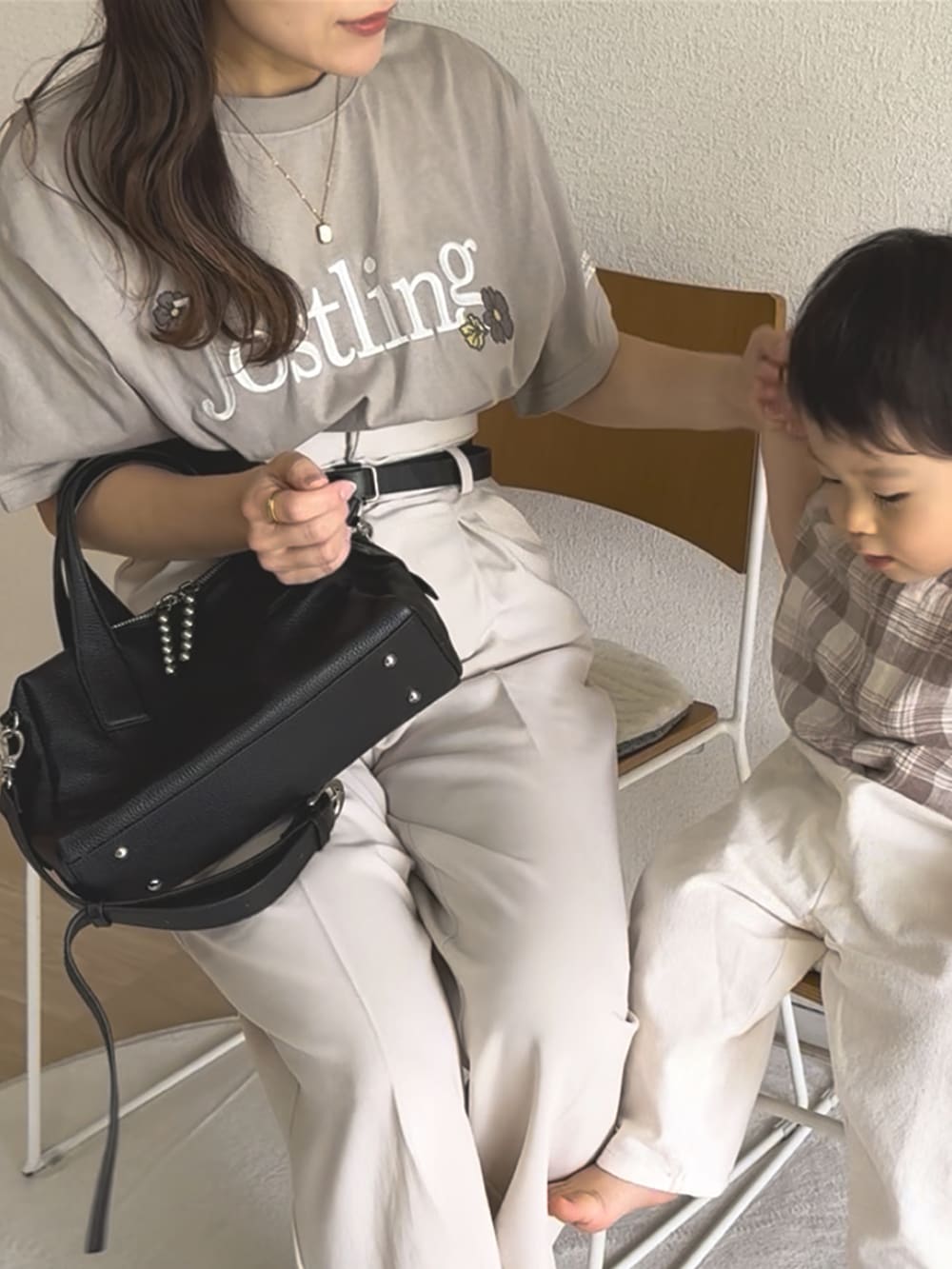 ホワイト系のスラックス、ブラック系のボストンバッグ、ベージュ系のTシャツ/カットソーを着用したレディースの秋コーディネートの4枚目の写真